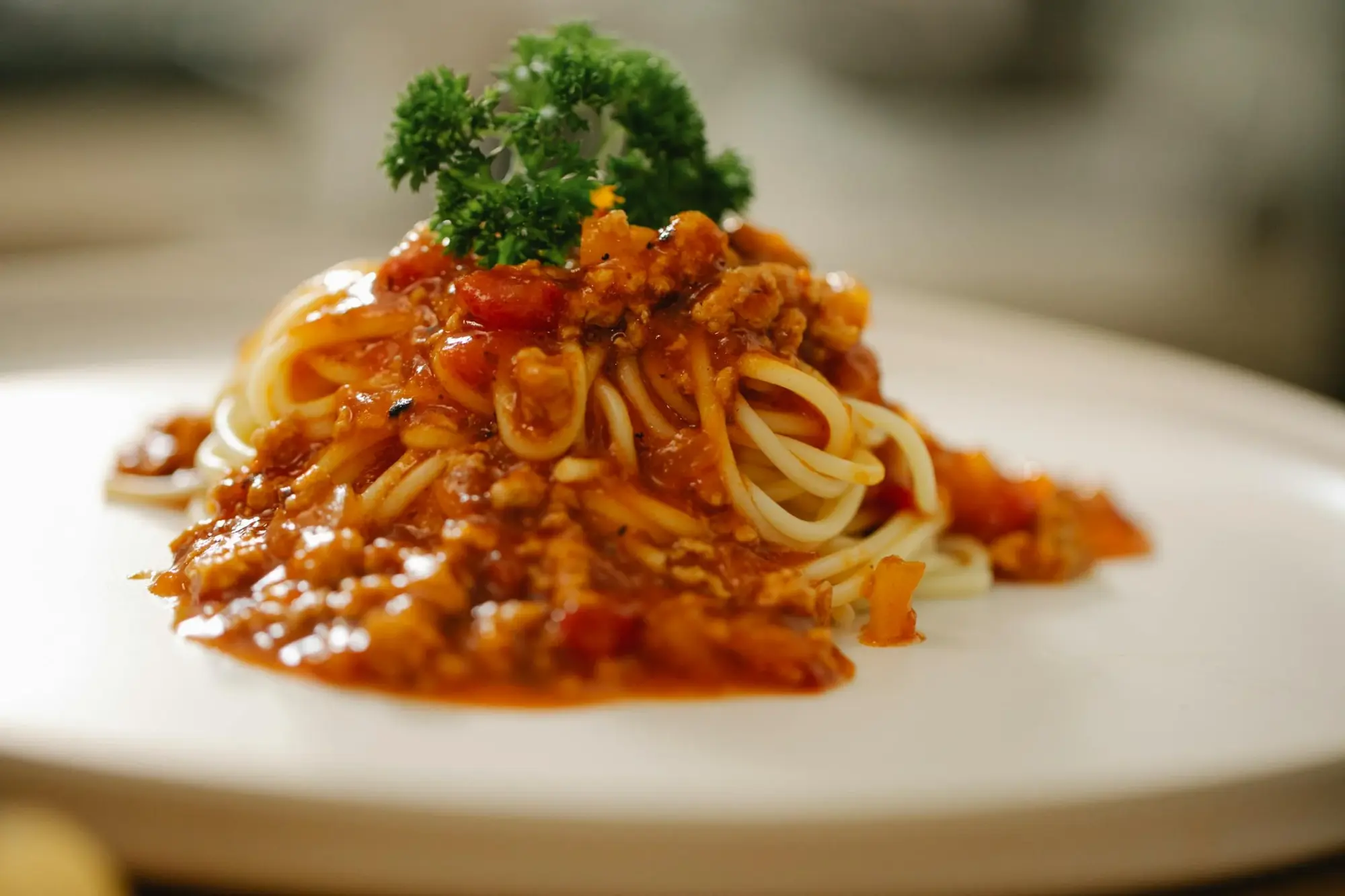 Spaghetti with red sauce on a plate garnished with parsley.