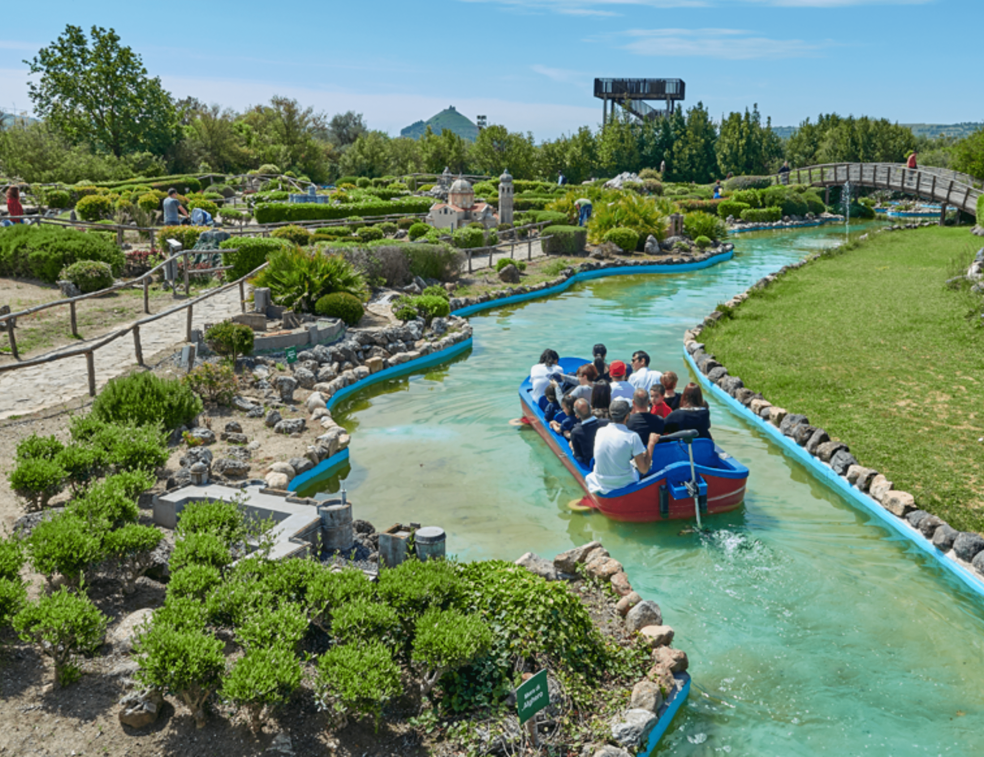 Tourists traverse calm waters aboard a boat surrounded by shrubs and greenery on a clear day.