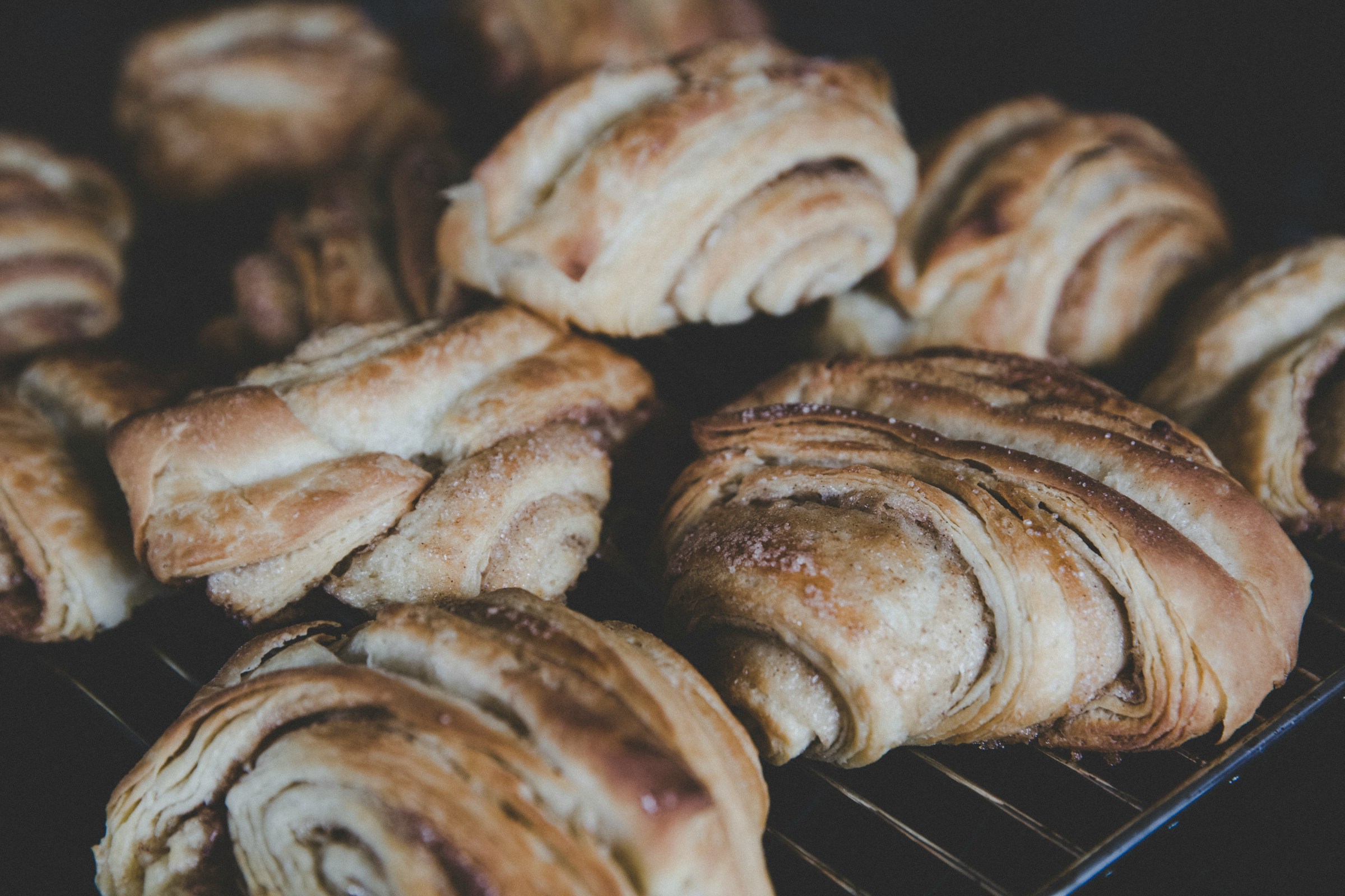 Croissants on a baking rack after being baked and looking very delicious.