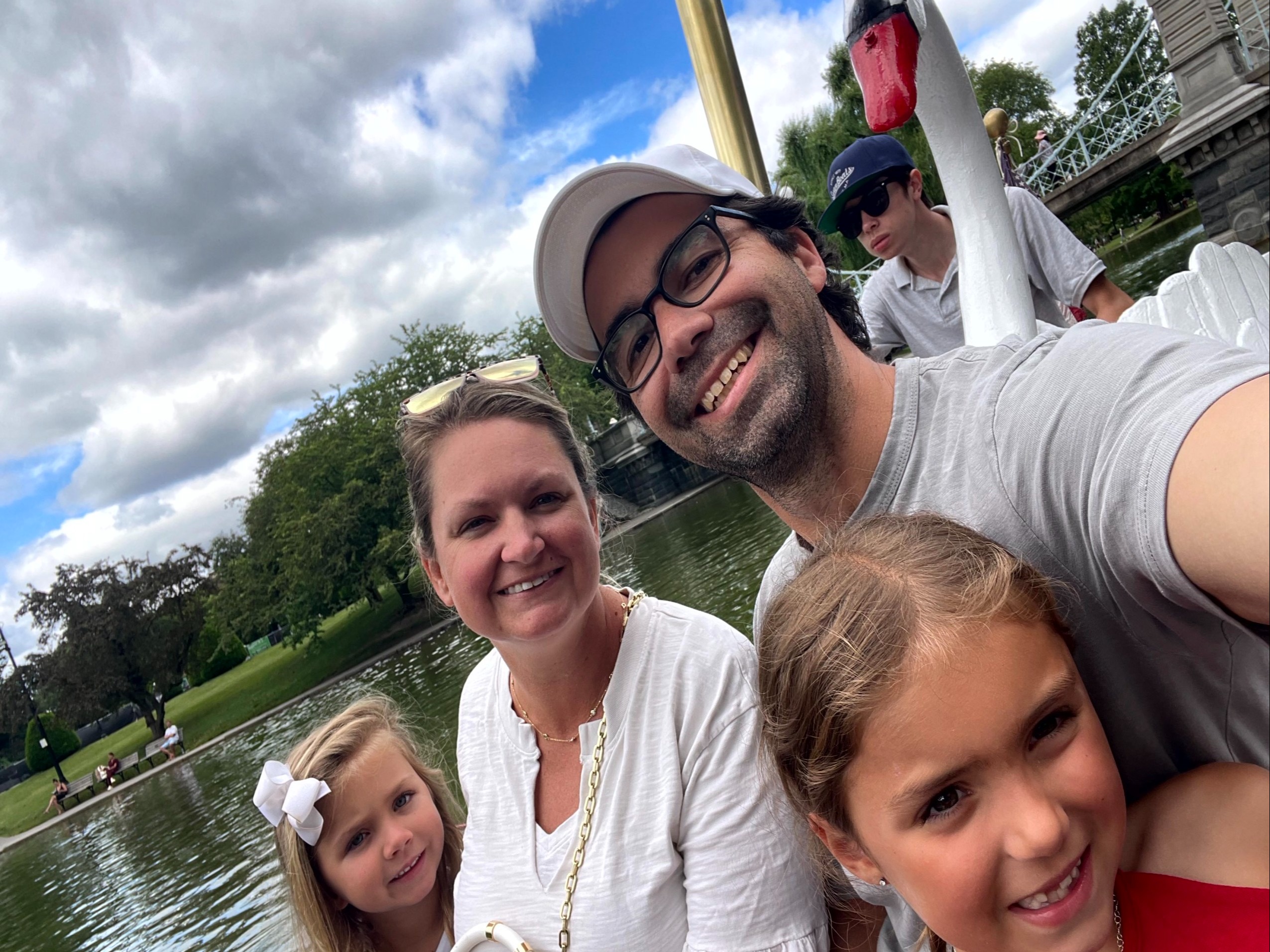 A family of four on a swan boat on a pond.