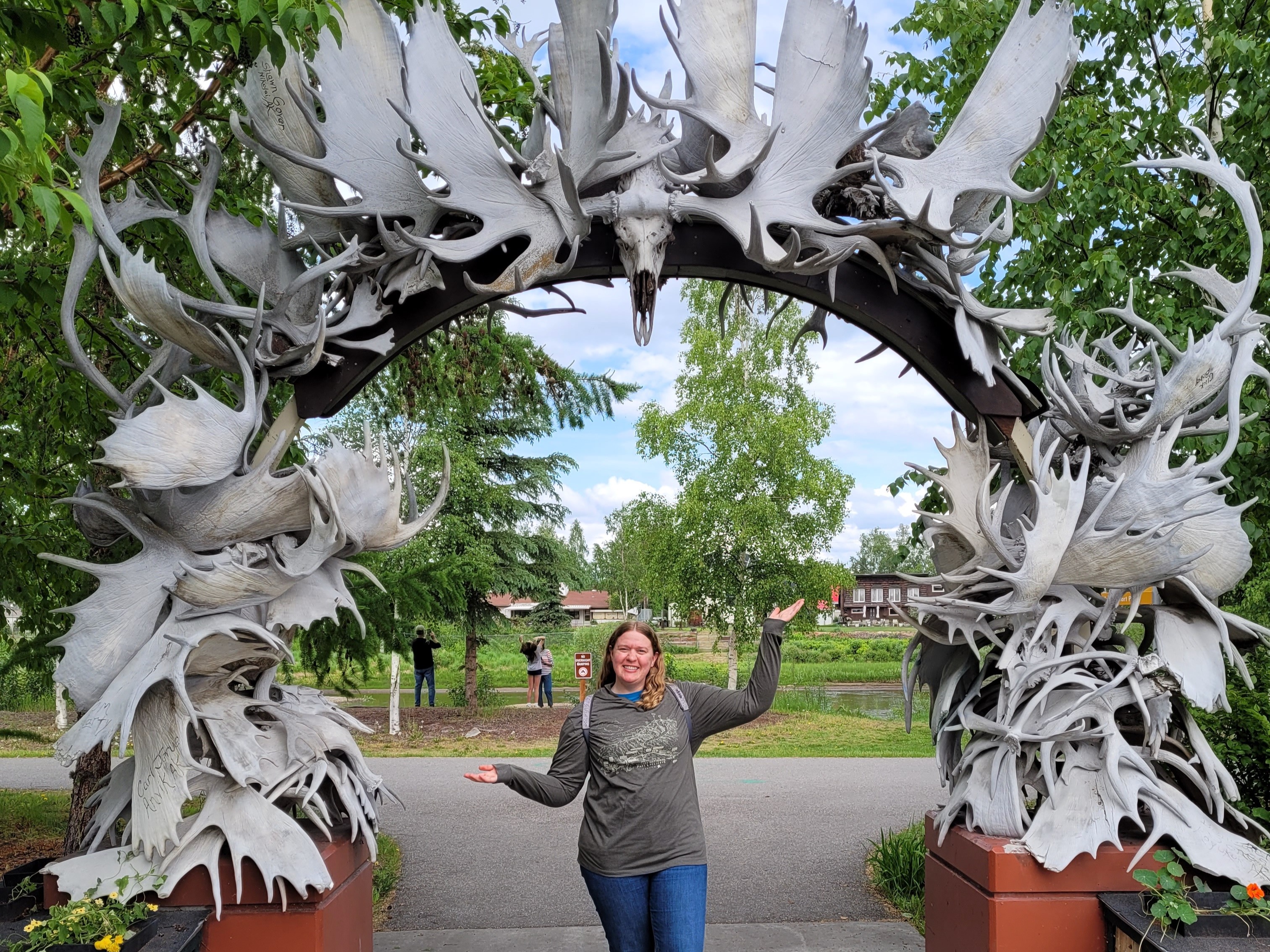 Beneath an archway of intertwined antlers, a person stands enveloped in the grandeur of nature’s artistry.