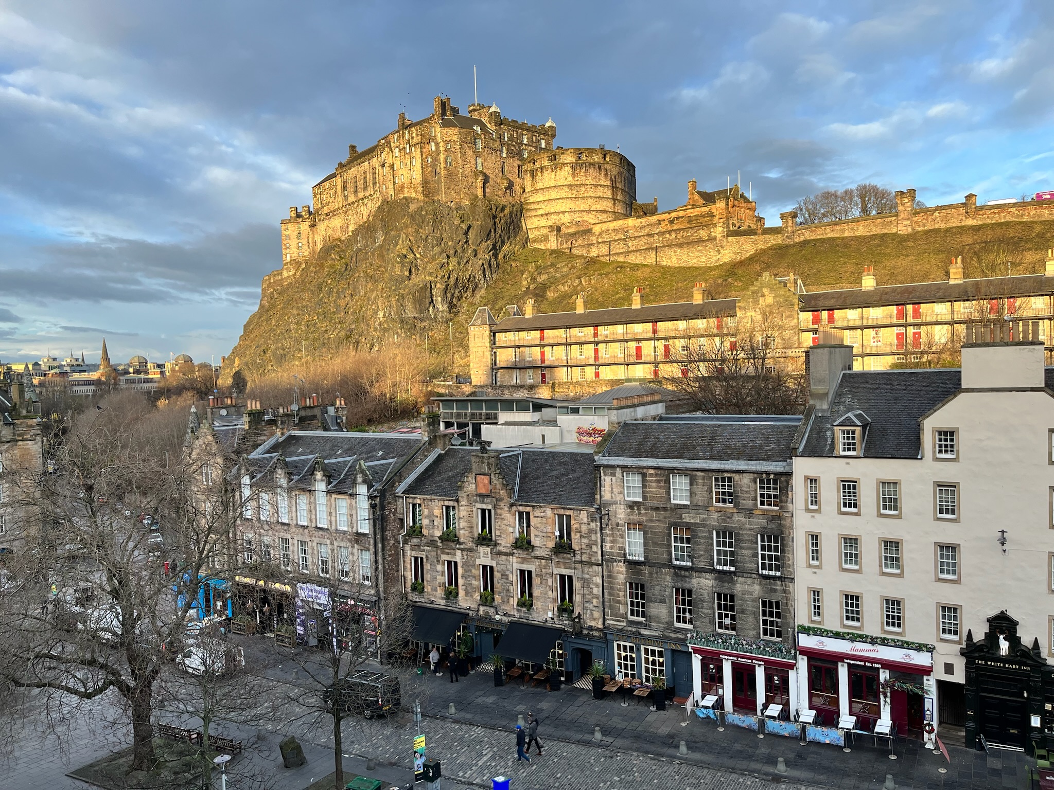 Edinburgh Castle on top of a hill with stone townhouses on the street below.