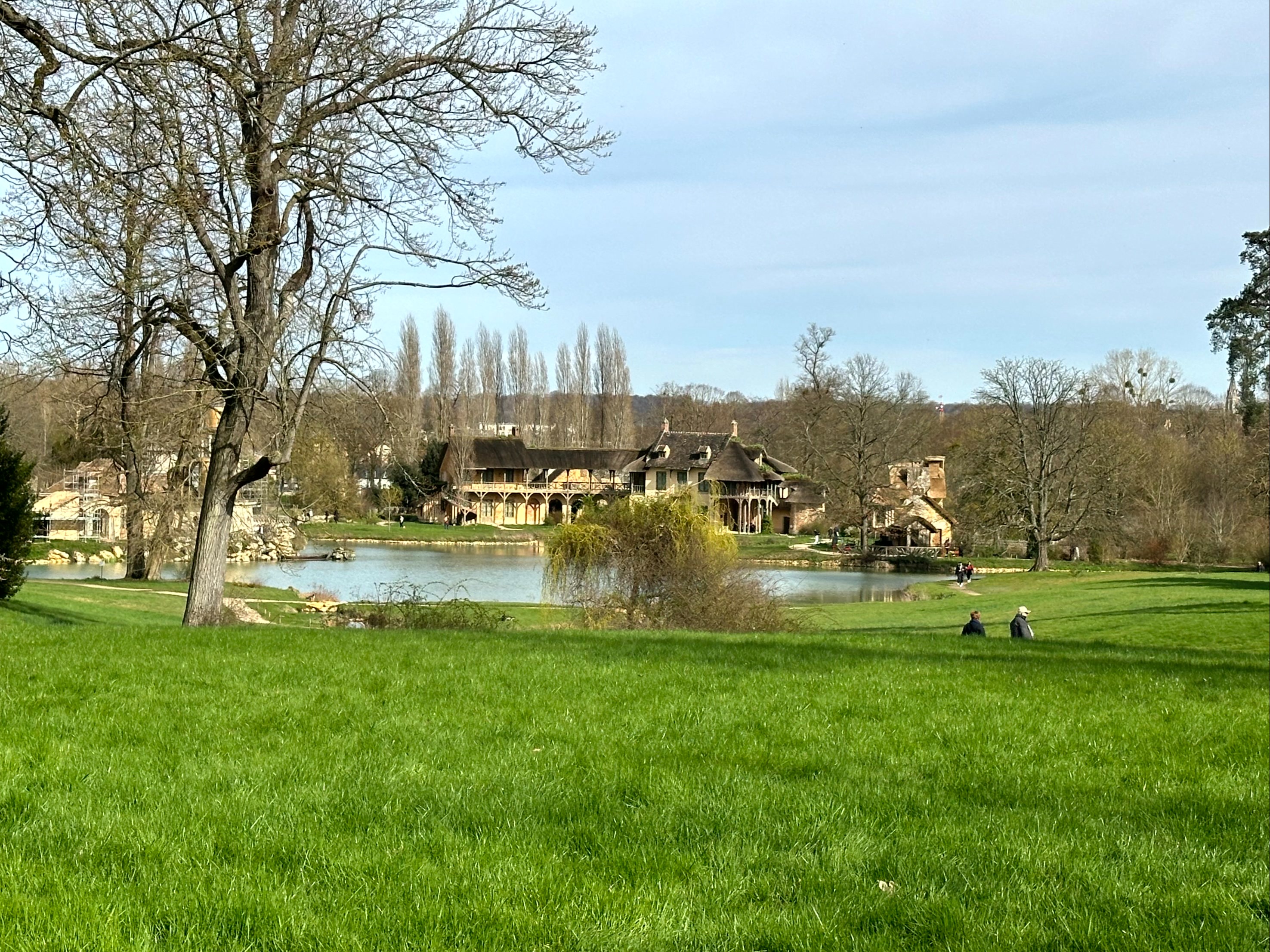 A picturesque thatched-roof house by a peaceful pond, embraced by verdant nature.