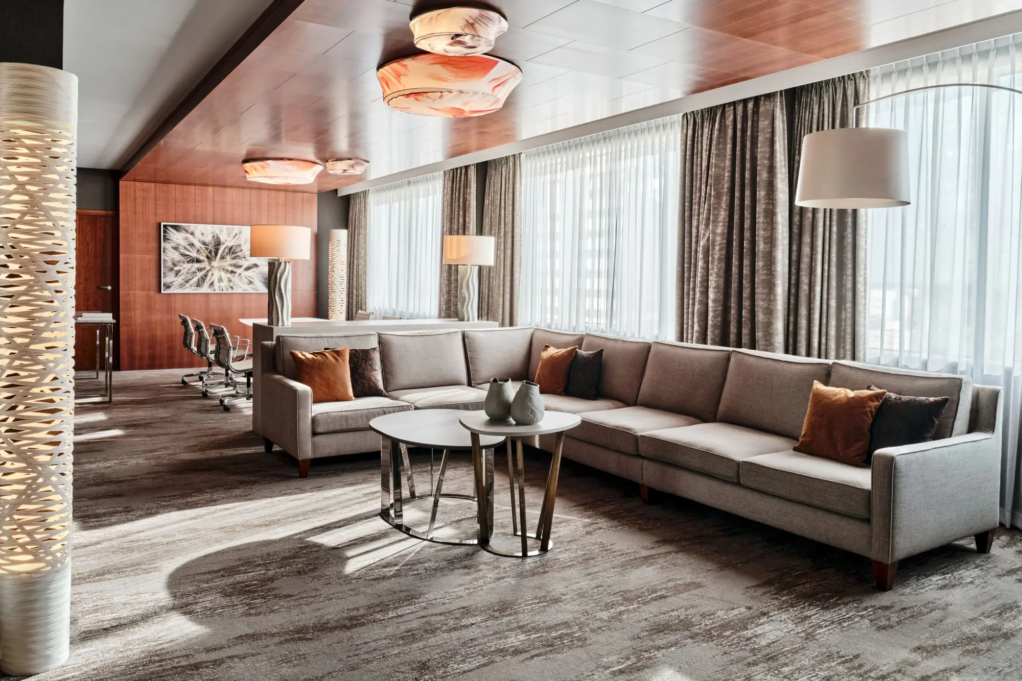 a gray L-shaped couch near a curved lamp in front of sunlit windows
