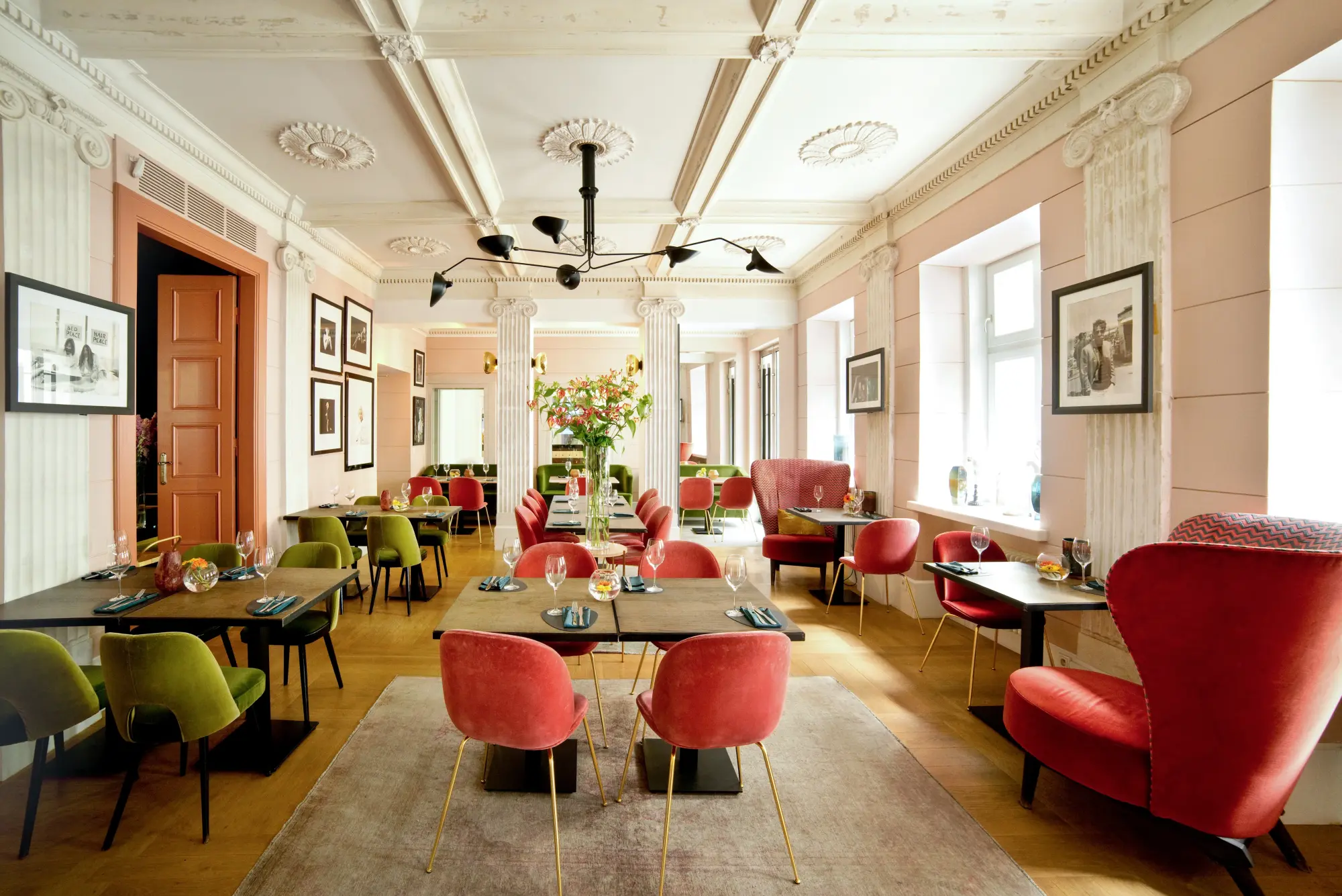 a sunlit dining room with red and green upholstered chairs