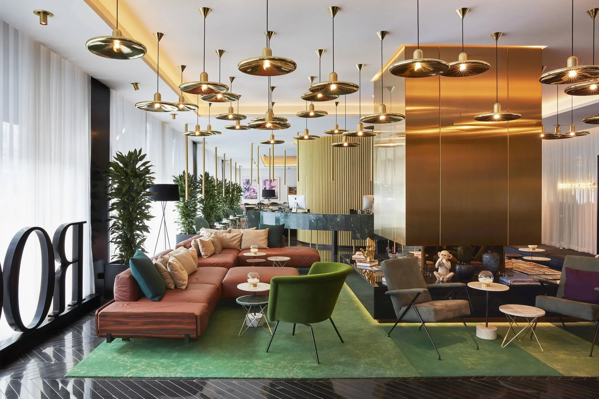 a hotel lobby with a red couch and green chairs on a green rug