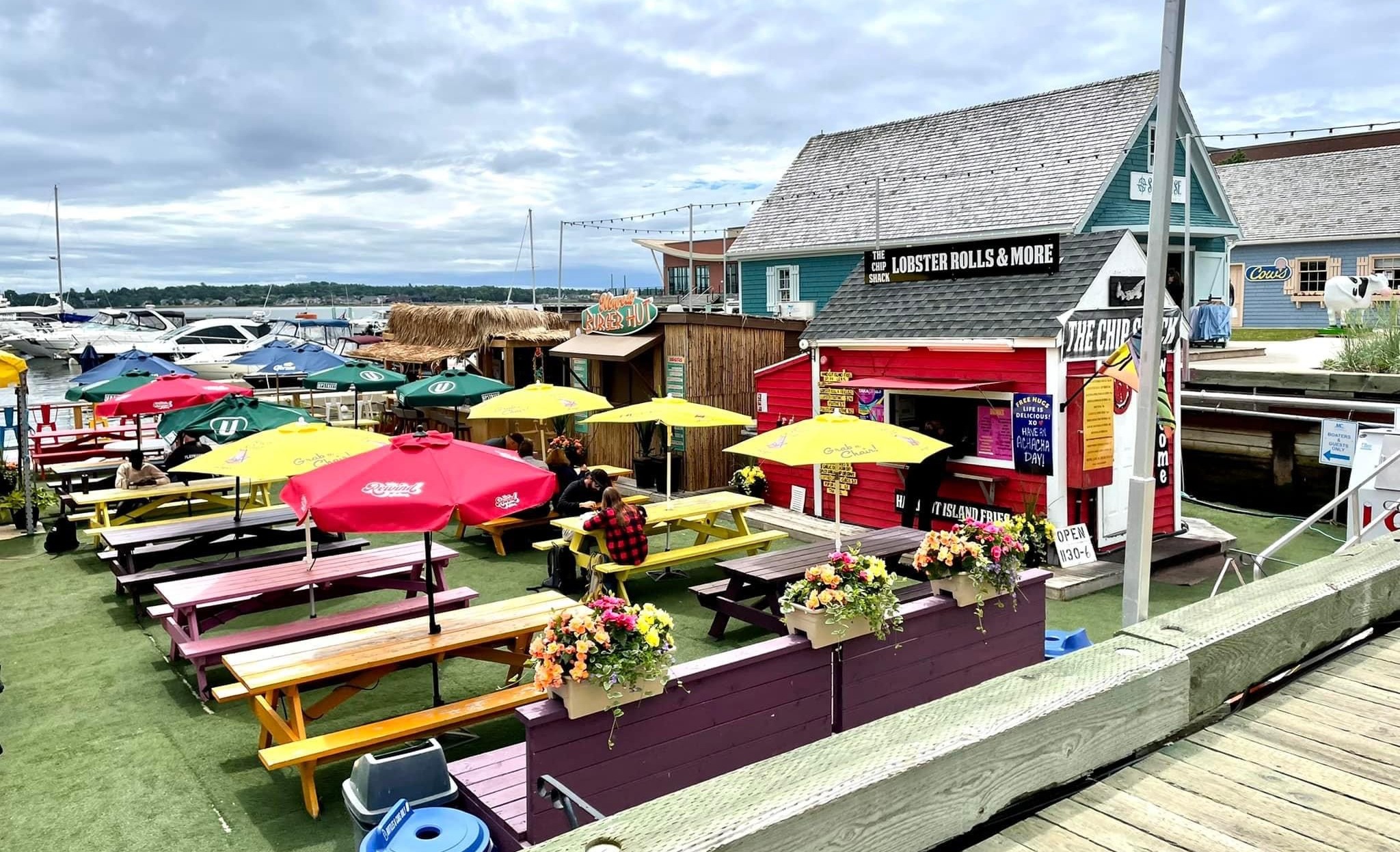 An outdoor dining area with benches and colorful umbrellas by some food trucks