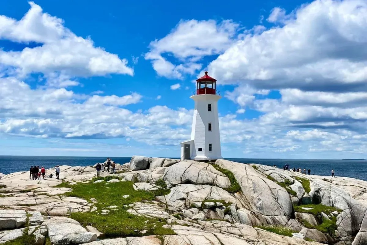 A lighthouse at Peggy's Cove on a rocky outcropping on a sunny day.