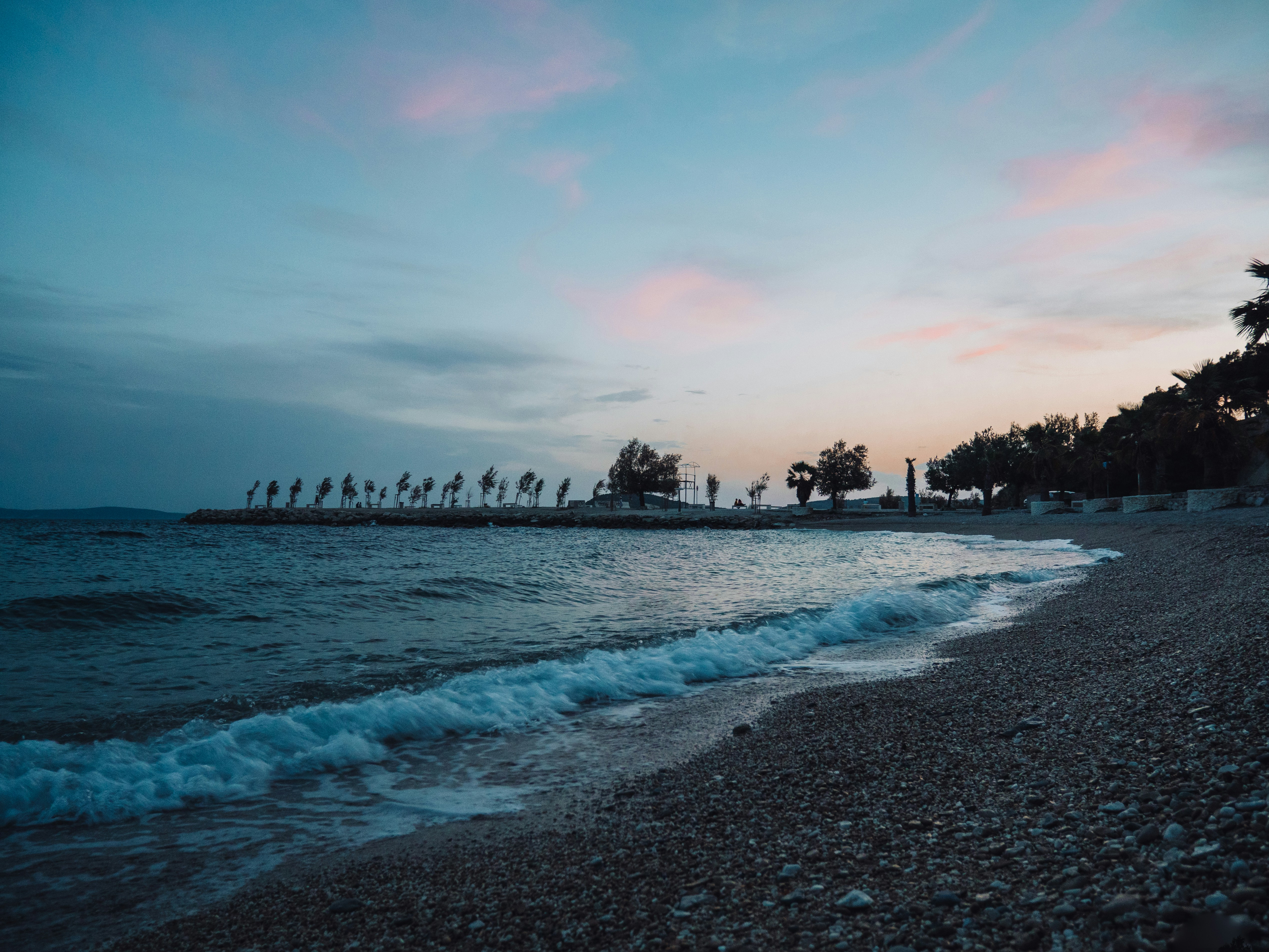 A rocky beach with waves coming onto the shore at sunset.