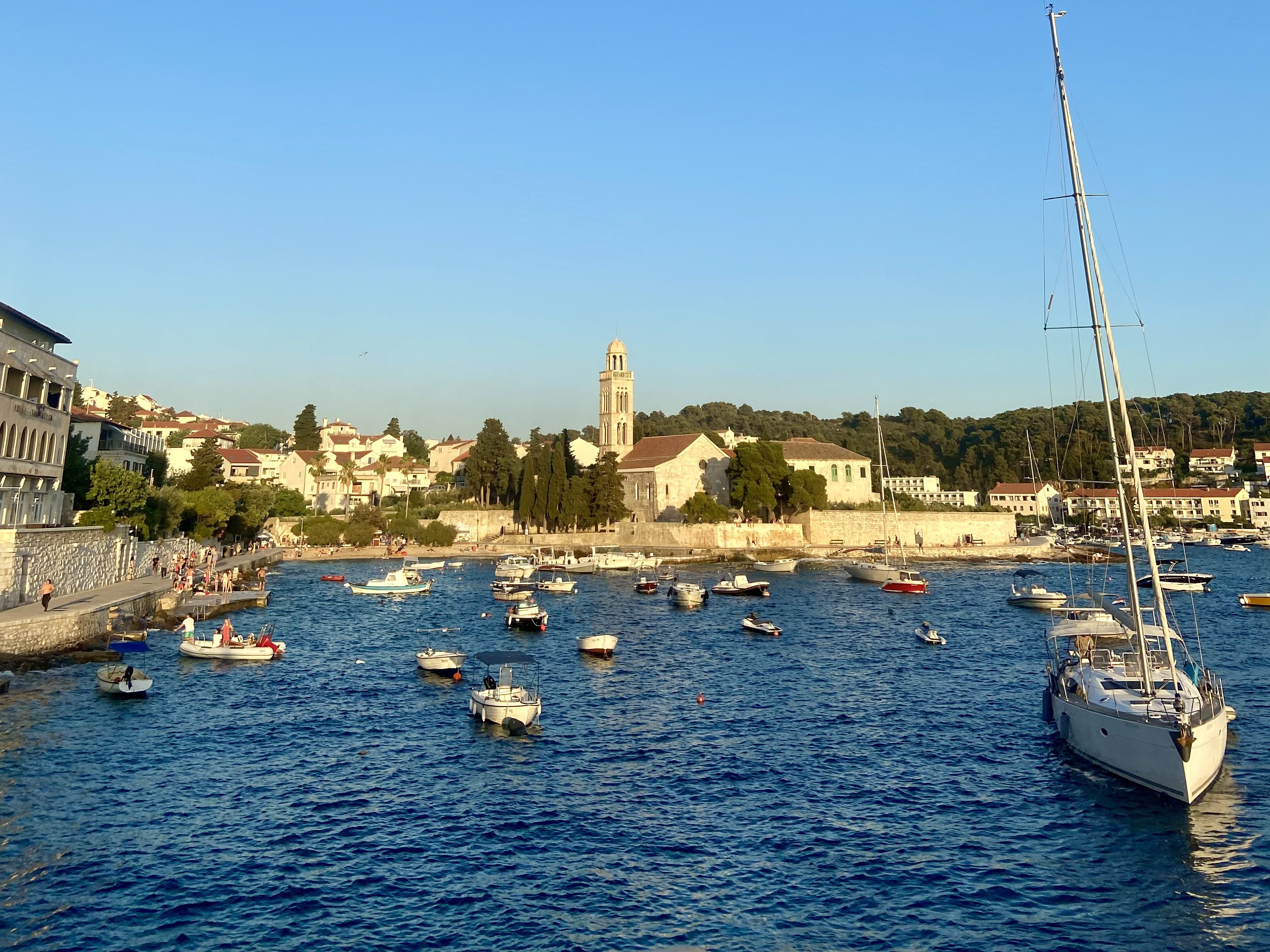 A picturesque view of a coastal town, with boats gently bobbing on the water and quaint buildings under the expansive blue sky.