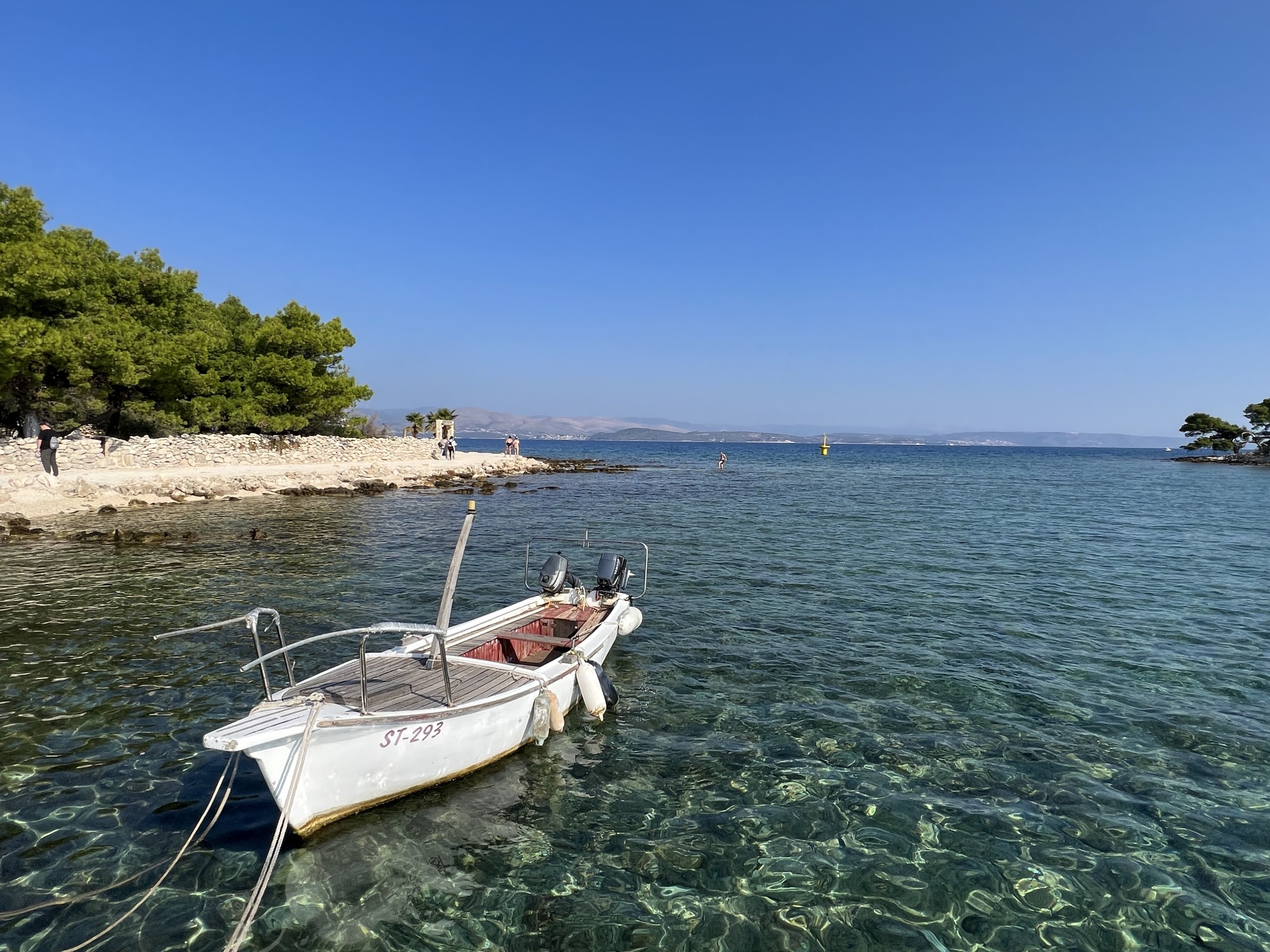 A white boat anchored in clear blue water during the daytime