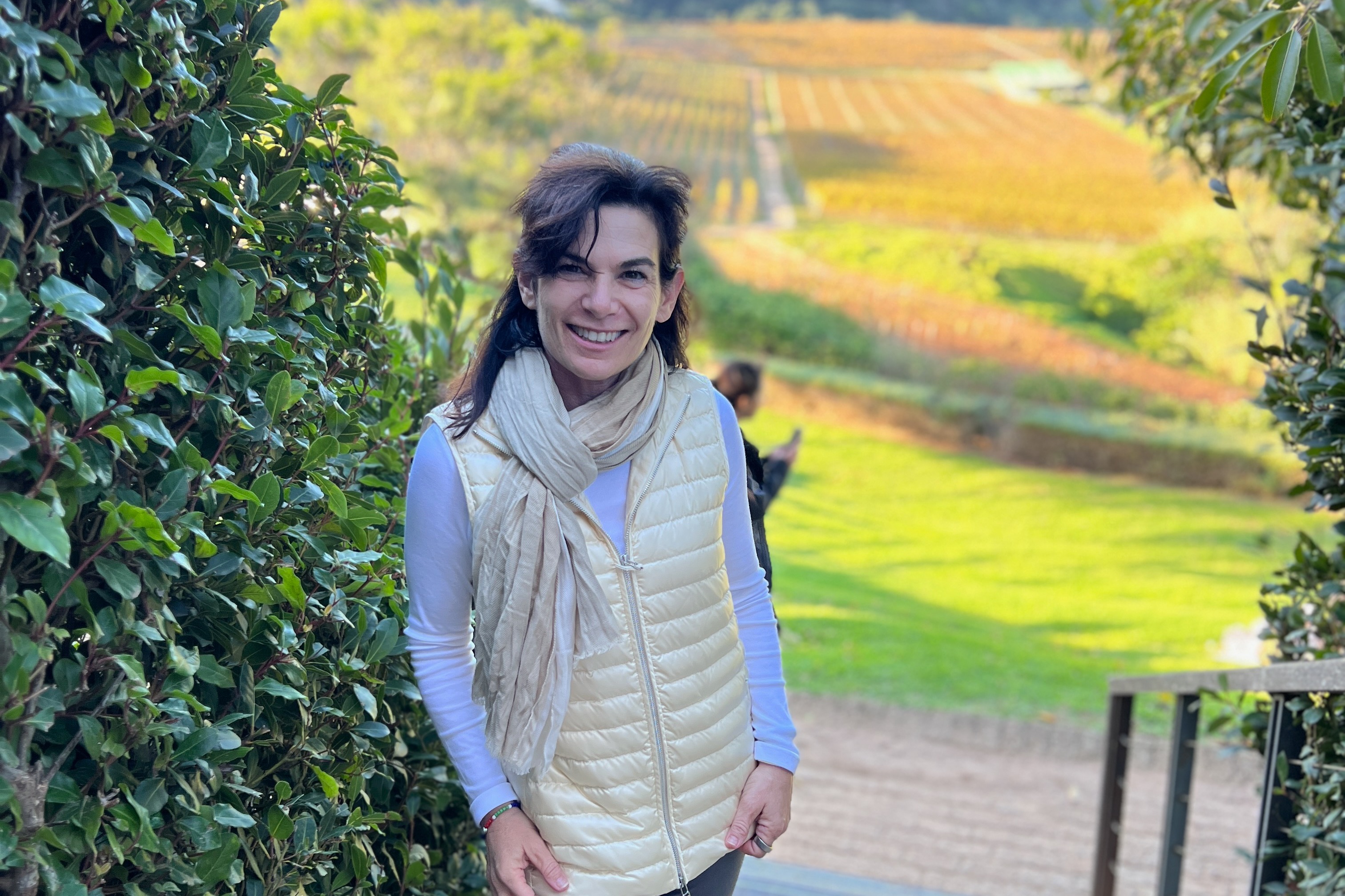Travel advisor Melissa standing with a beautiful view of a vineyard behind her.