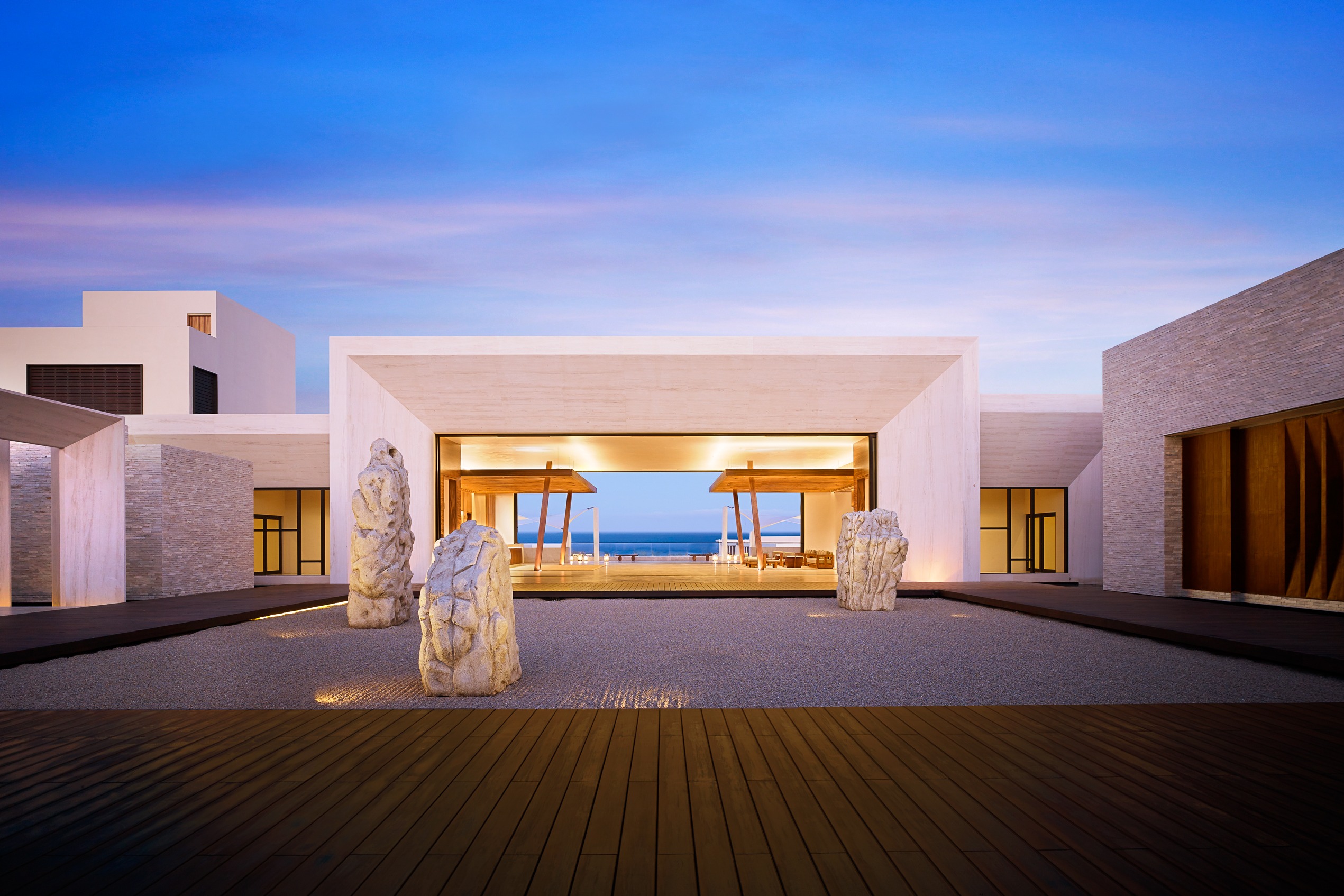 zen looking entrance to hotel lobby framed by rectangular white structure with sea beyond