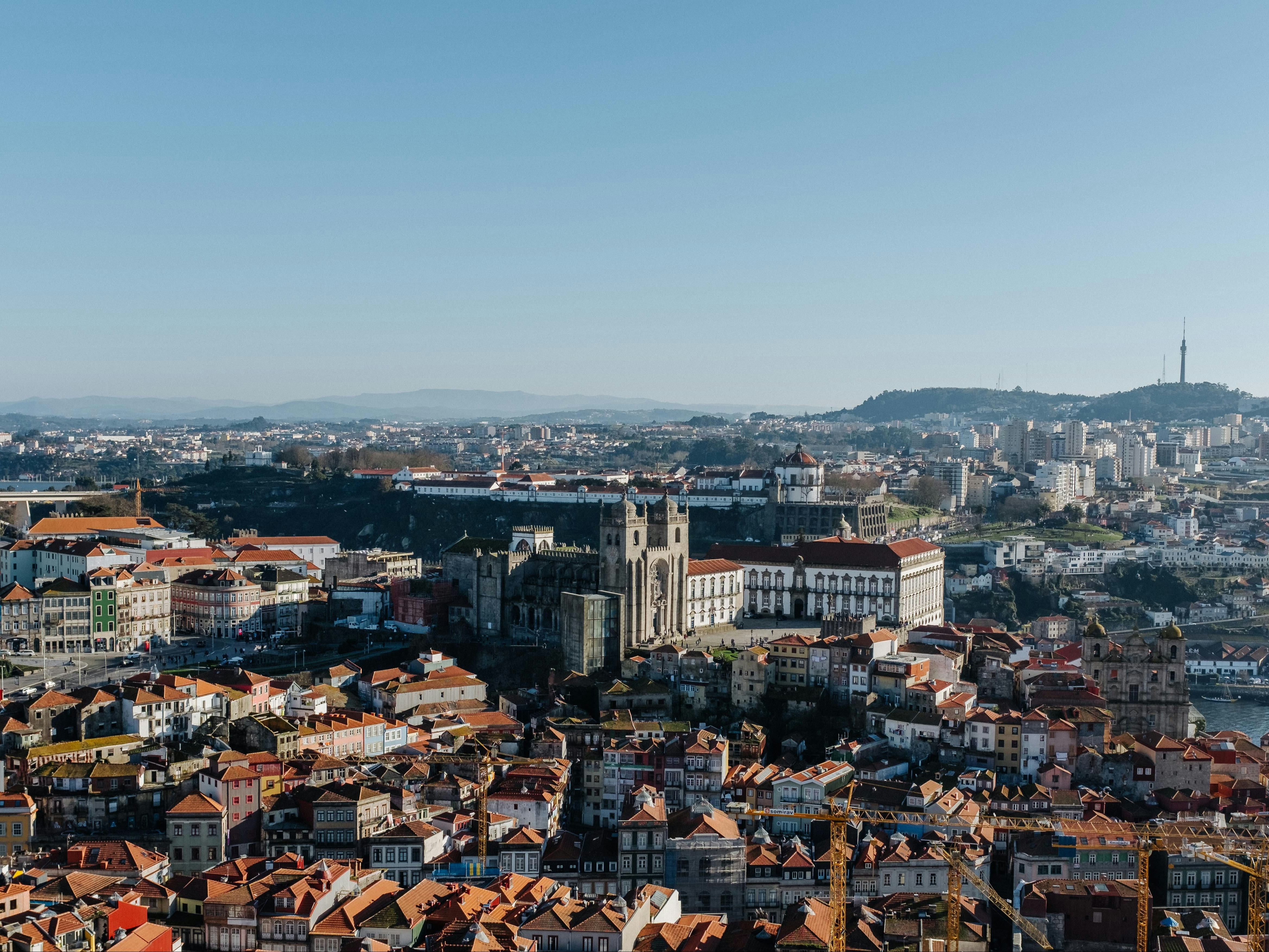 The image presents a panoramic cityscape with densely packed buildings under a clear sky.