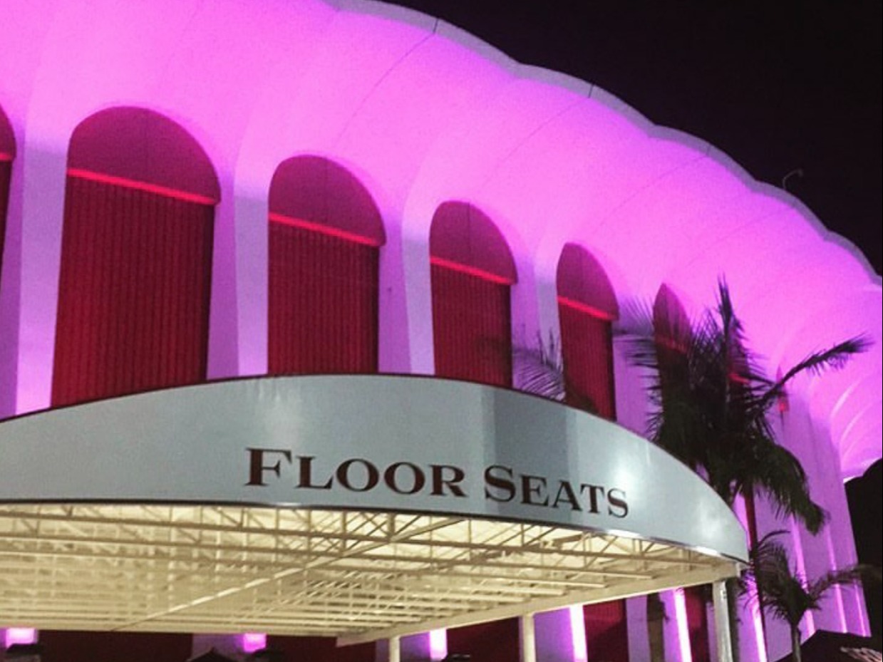 A music venue in Los Angeles illuminated with purple light and a sign on the entrance saying "Floor Seats"