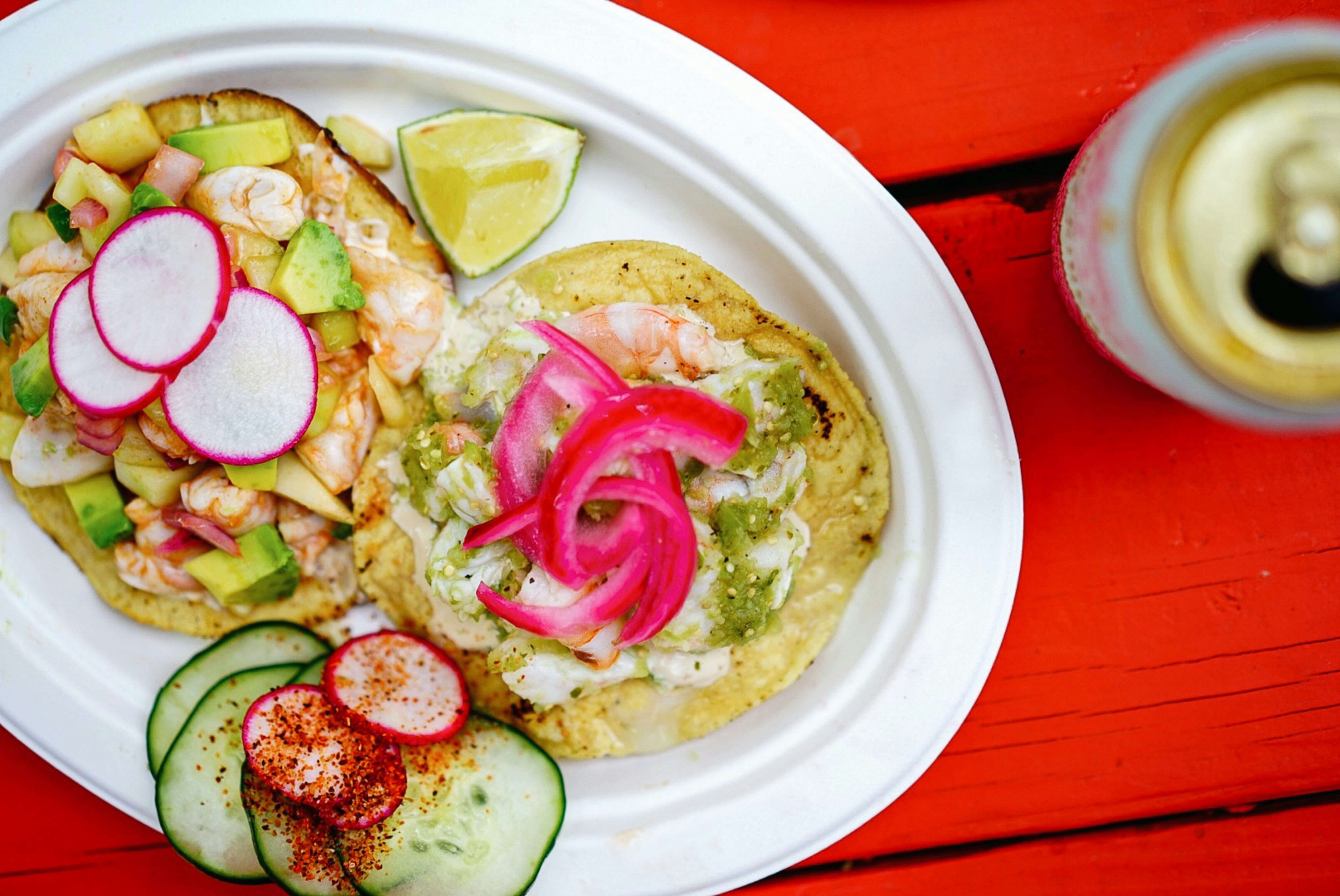 A white paper plate with tacos on a picnic table.