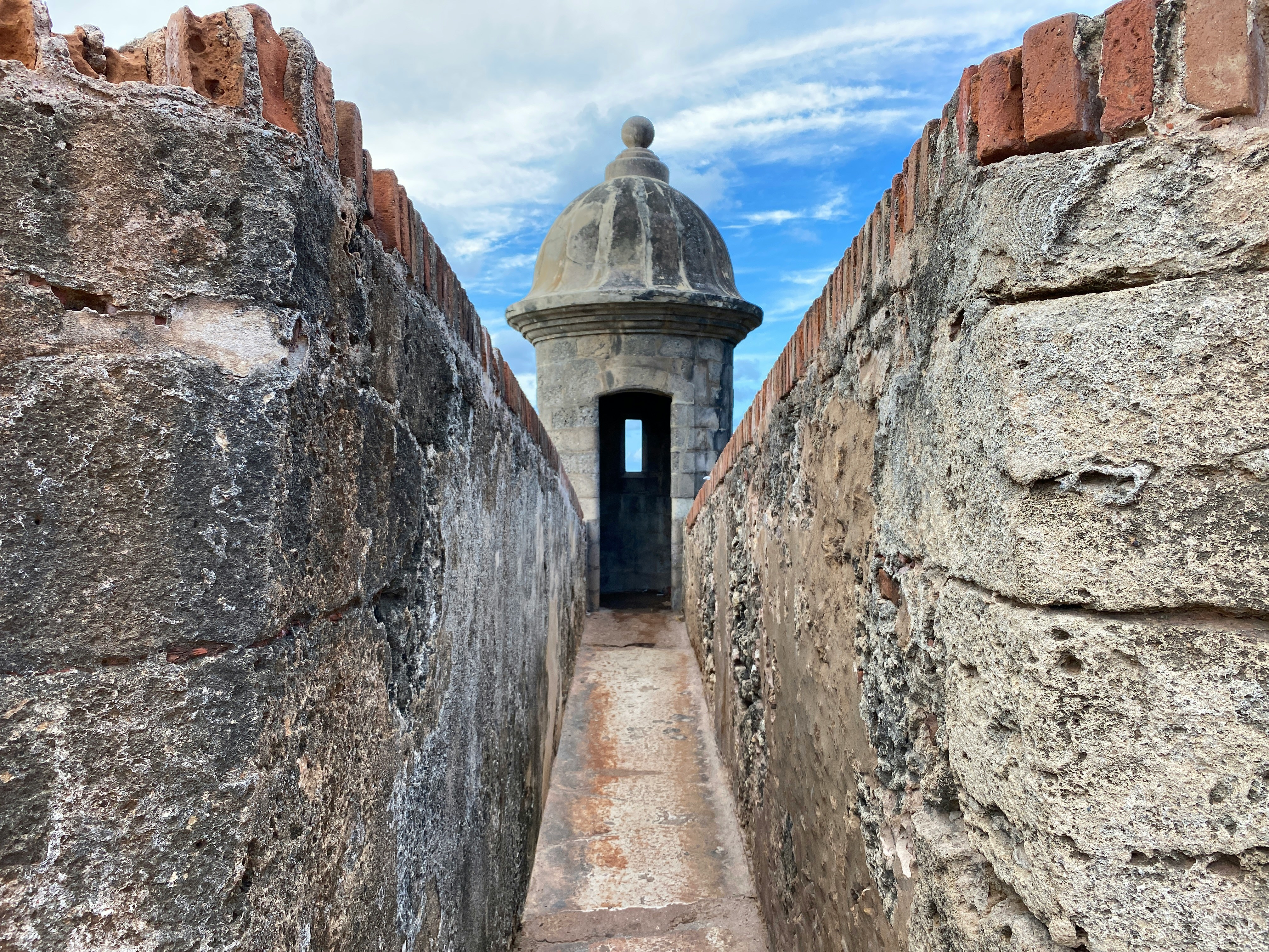 Castillo San Felipe del Morro, with stone walls leading to a turret on a sunny day.