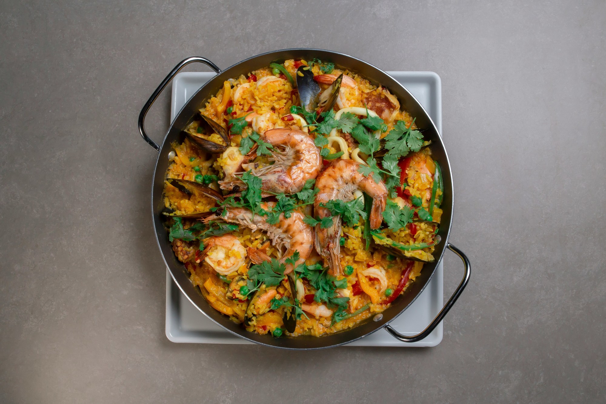 This image depicts a pan full of paella on top of a blank countertop.