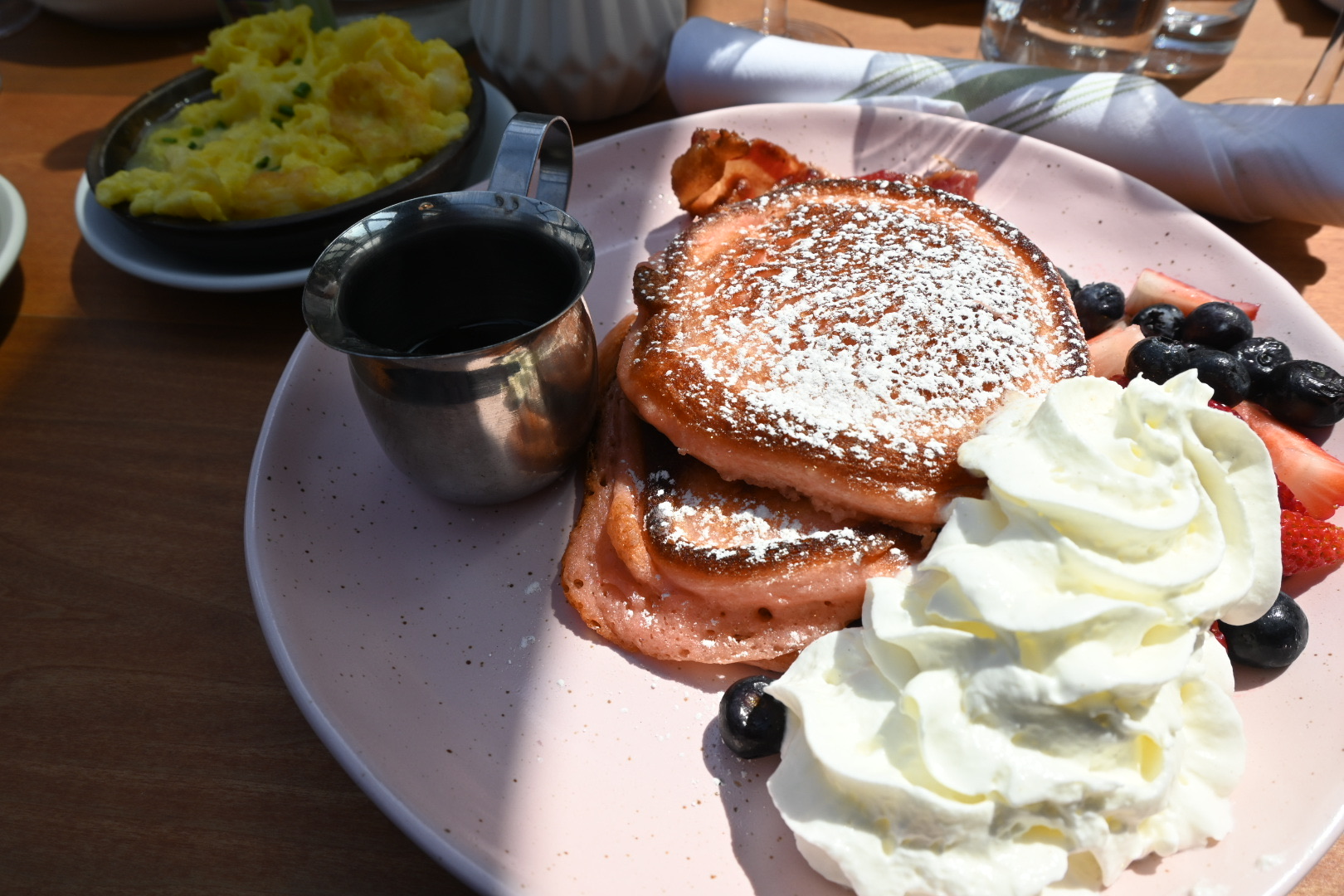 A plate of pancakes, cream and fruit at a restaurant.
