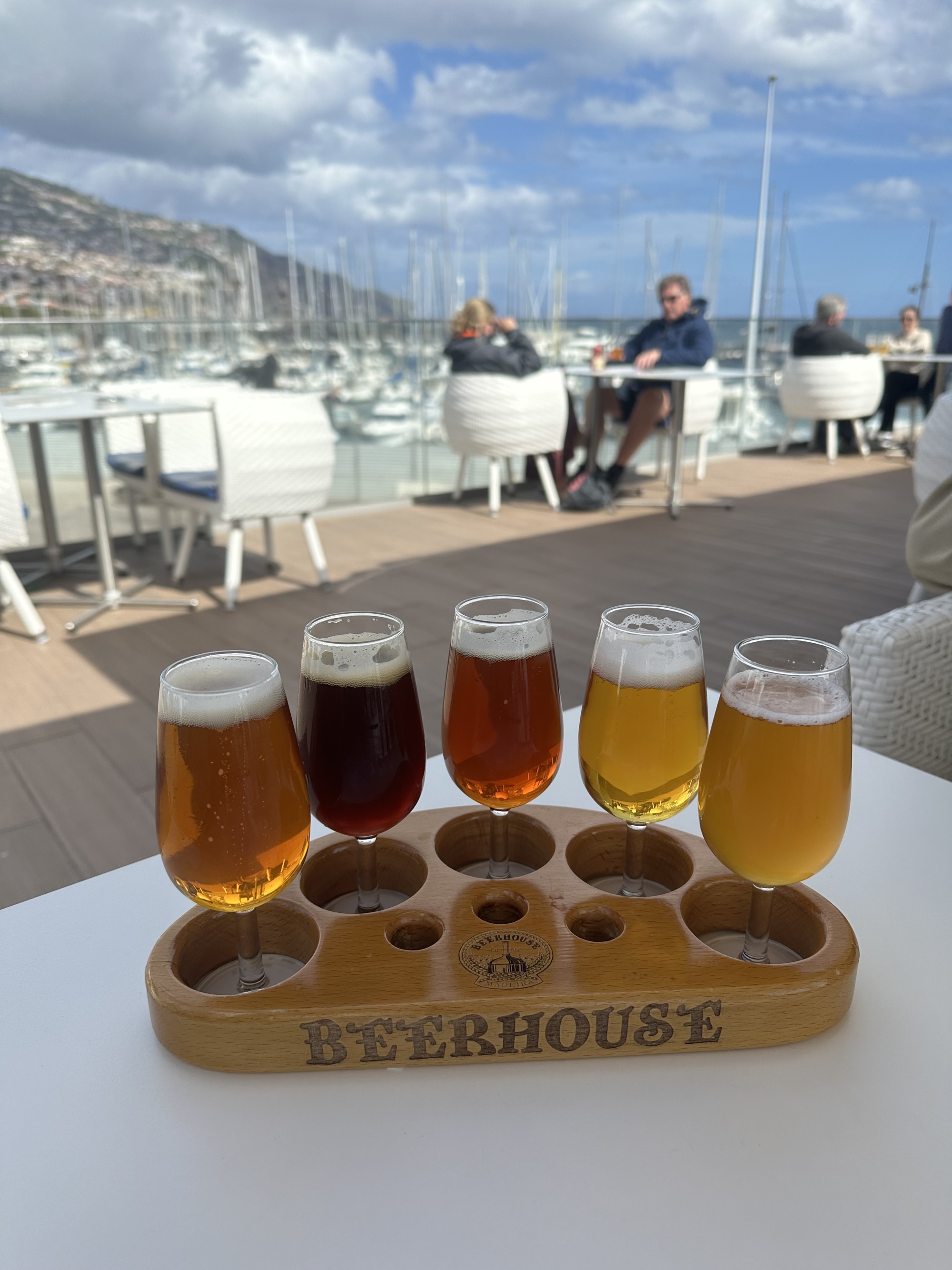 Beerhouse's tasting flight with five different beers, all a different color or shade, placed on an outdoor table overlooking the nearby marina.