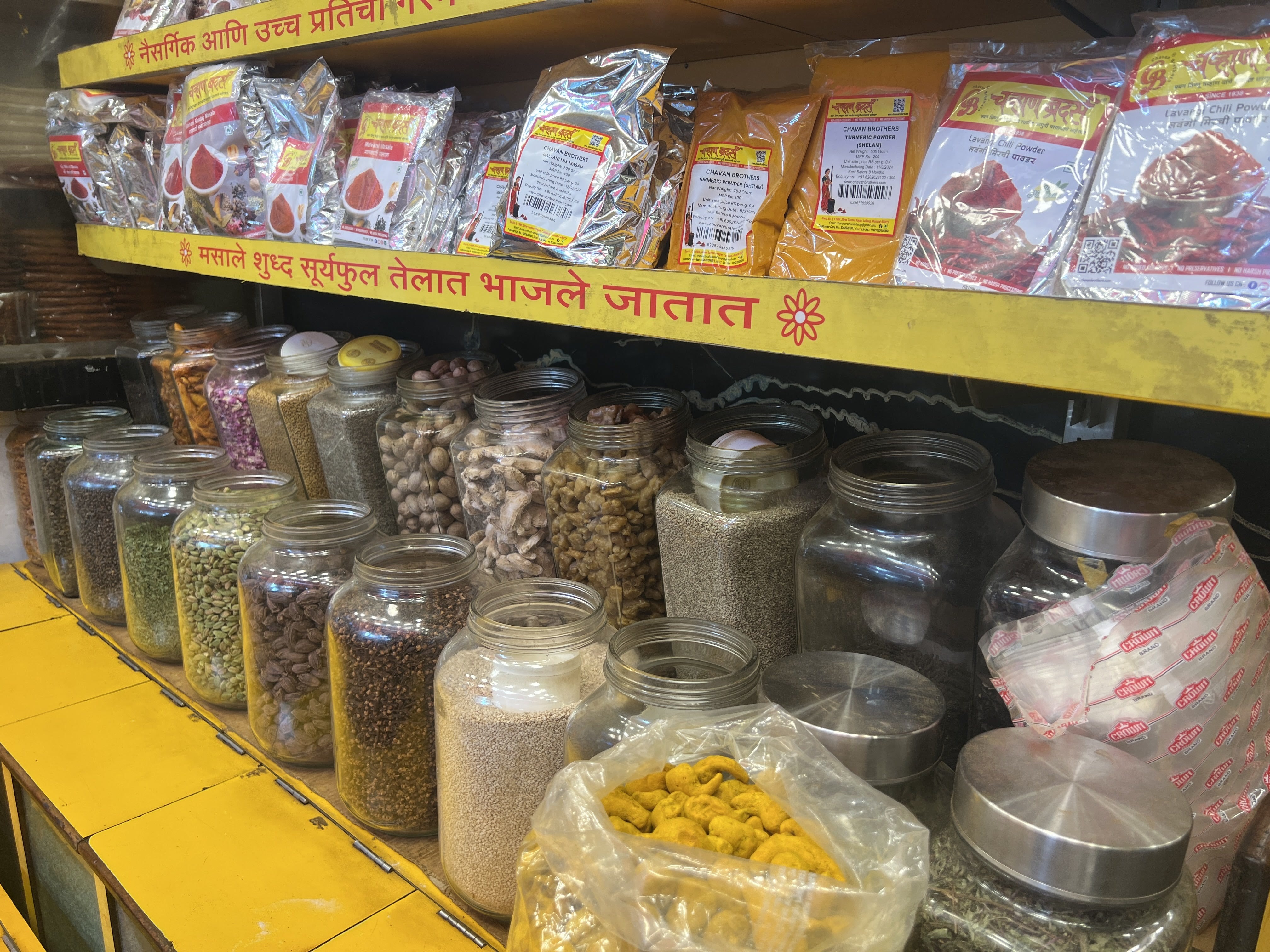 A colorful assortment of spices and legumes in a traditional Indian grocery setting, highlighted by Hindi signage.