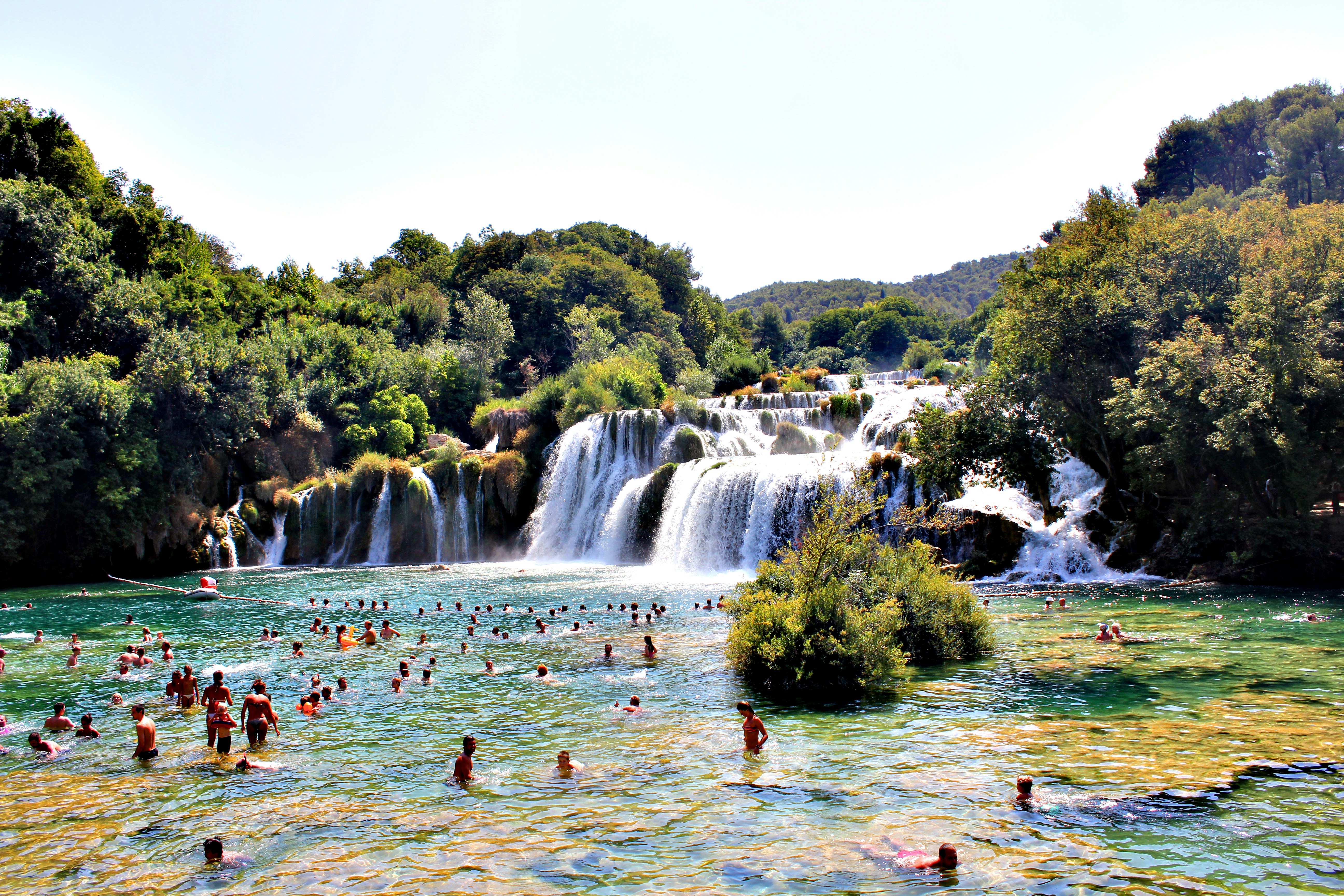 People enjoying a refreshing cool-off in Krka National Park's natural pools that its majestic waterfalls effortlessly flow into.