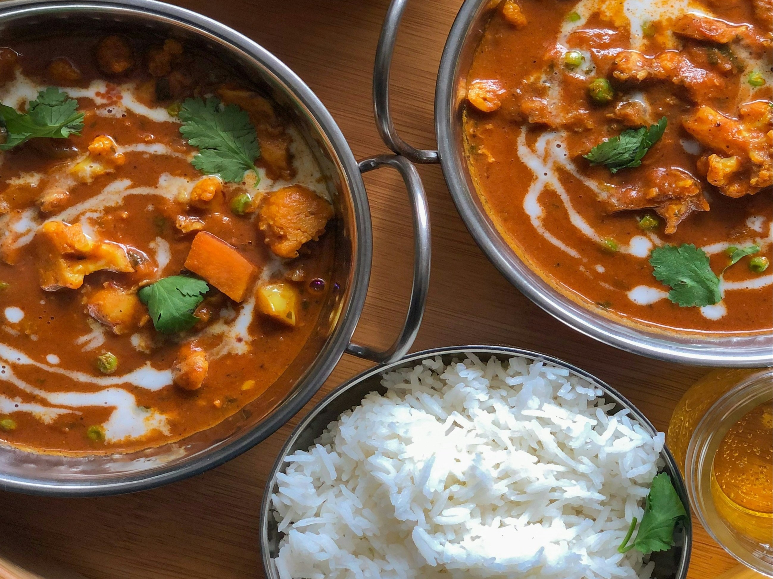 The image presents a neatly arranged meal with rice, curry and drinks, ready to be enjoyed on a wooden surface.