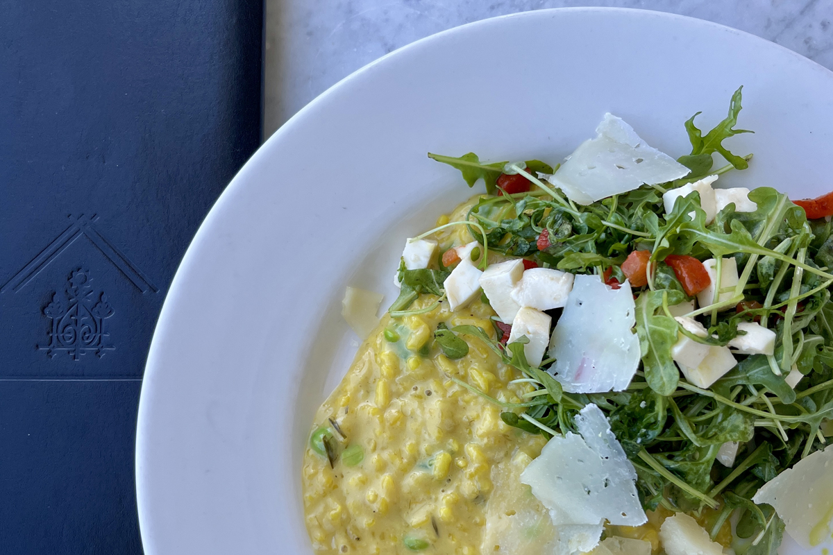 A white plate with creamy risotto next to a salad