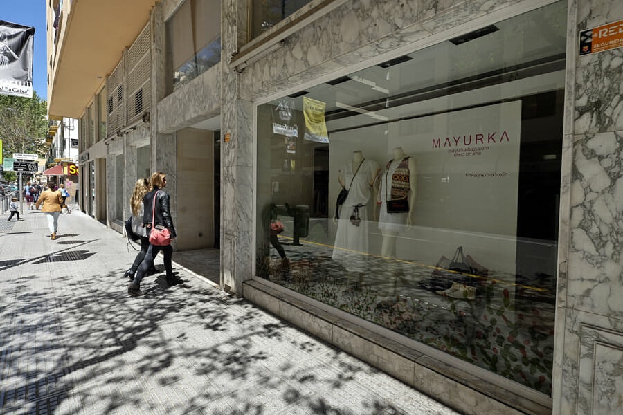 A woman walking along a street and window-shopping at upscale shops in Ibiza, Spain.