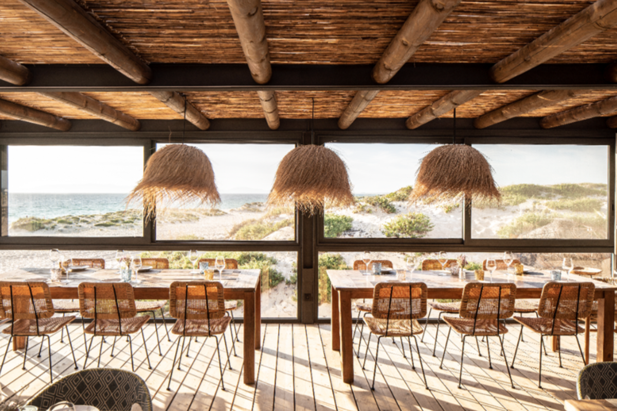 an airy outdoor restaurant with grassy light fixtures overlooking the ocean