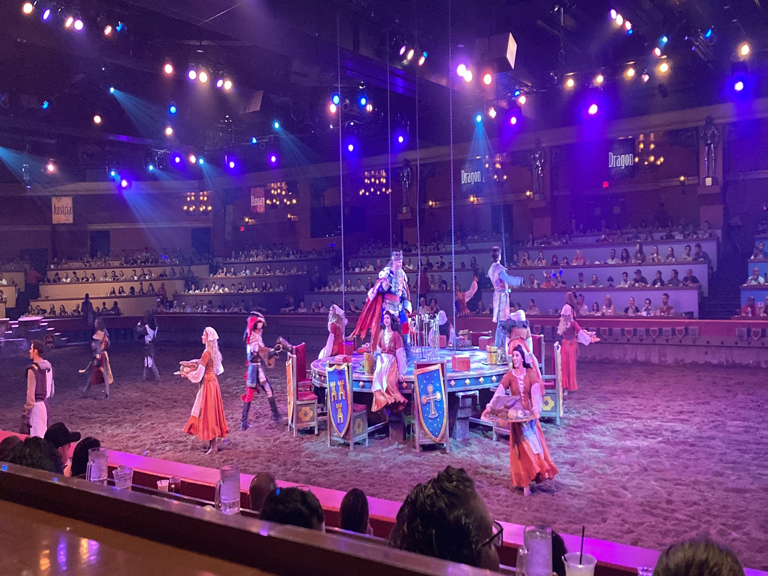 A lively medieval-themed performance with actors in costumes entertaining an audience at a dinner show.