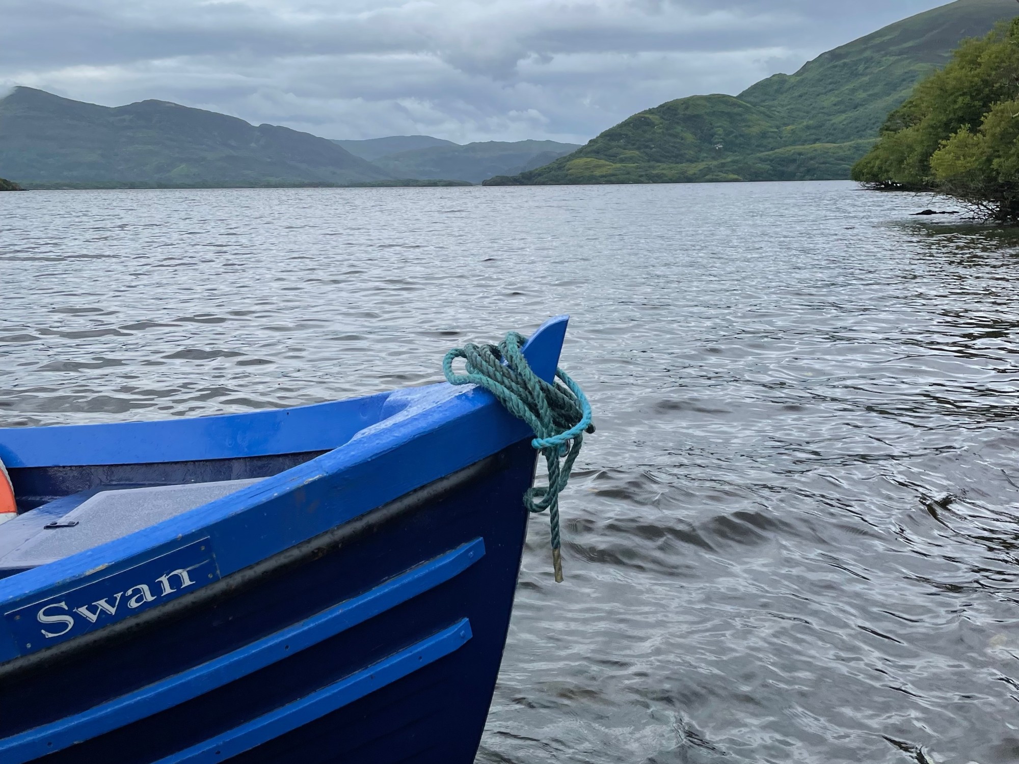 The edge of a blue boat on a river.