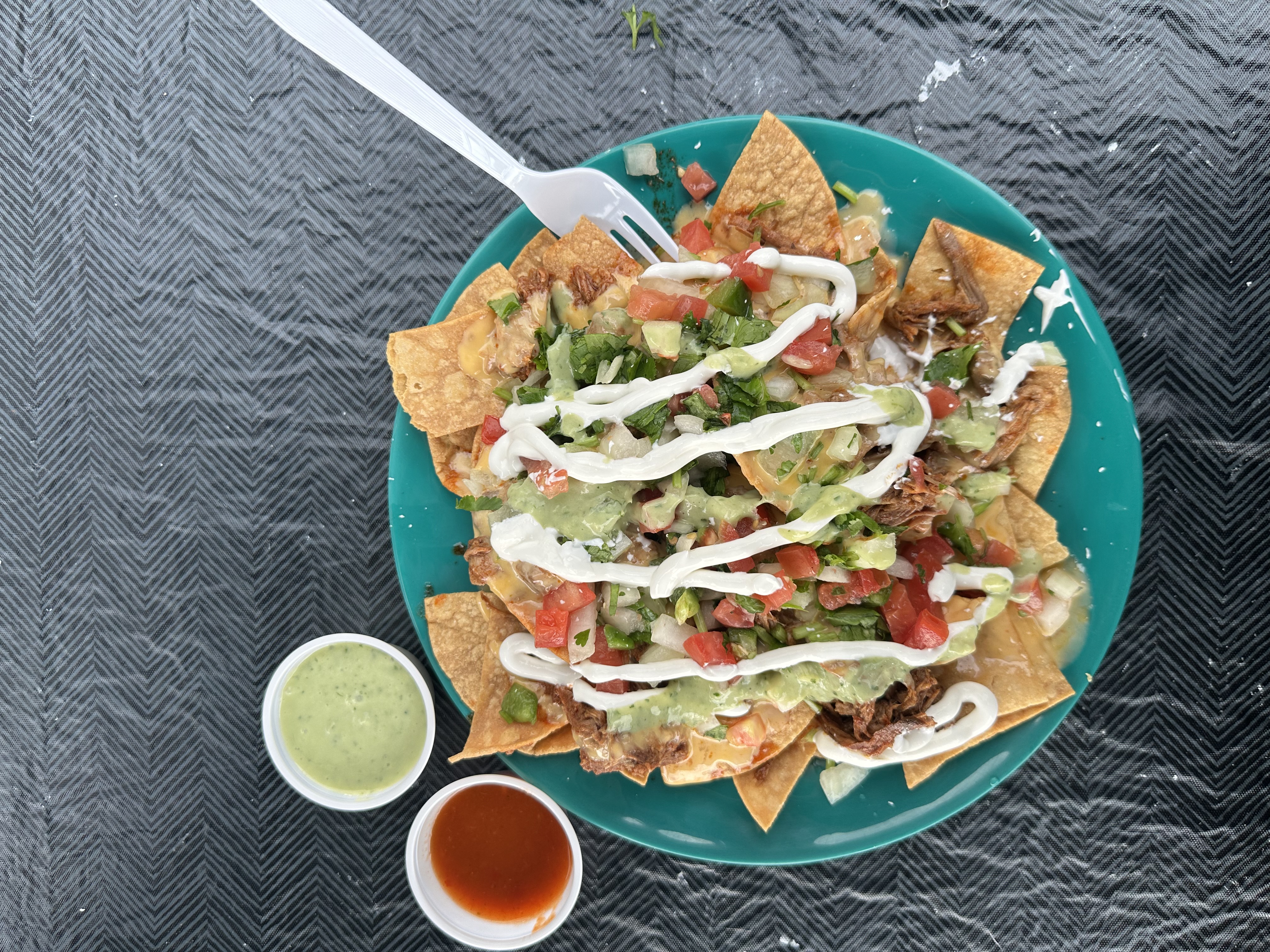 A plate of nachos with a white plastic fork