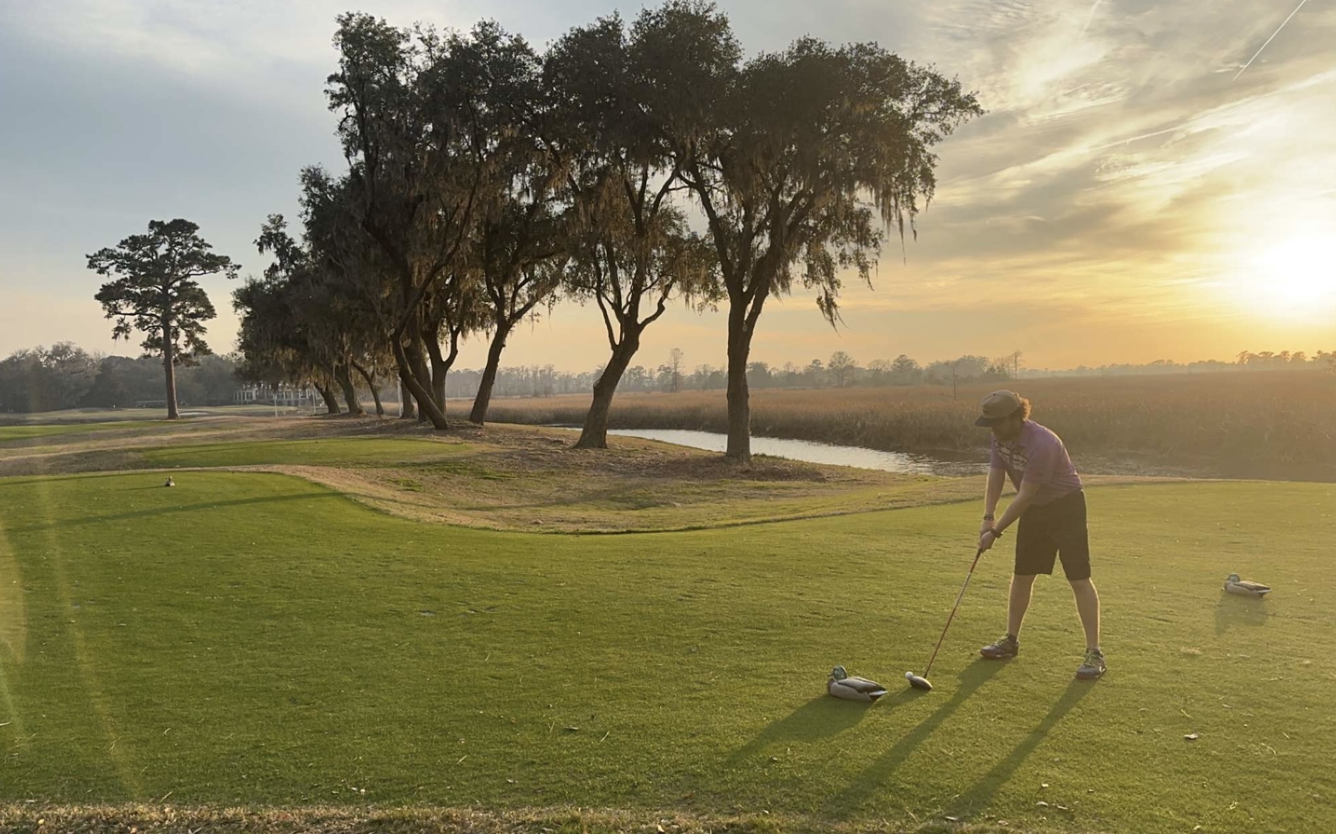 A man playing gold on a course with the sunset in the background