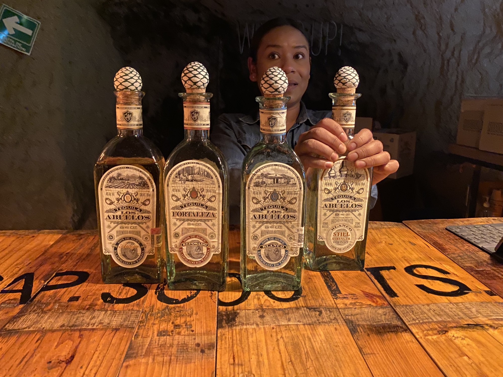Four bottles of tequilas in front of a woman.