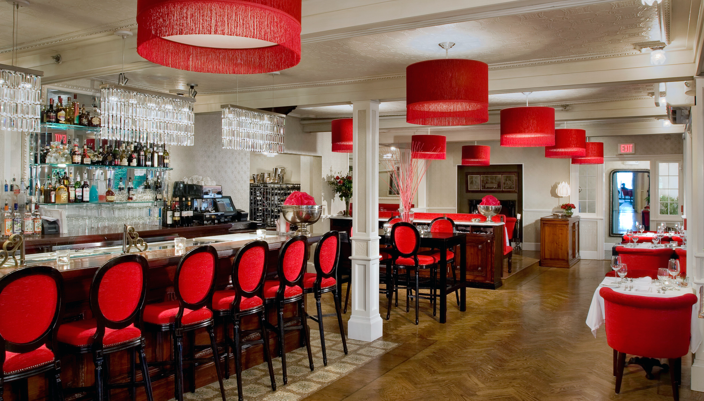 A classic restaurant with red interior and fringe lights with bar seating.