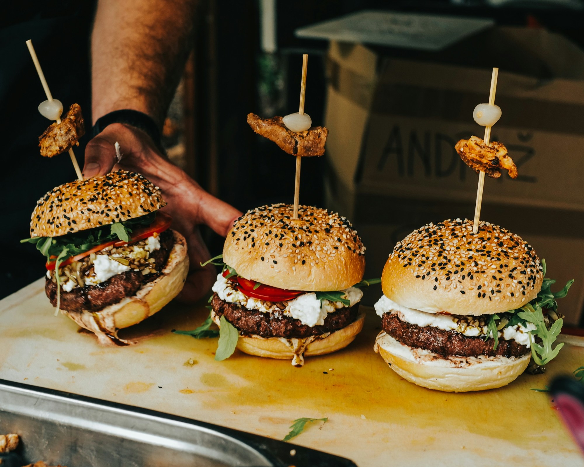 Three burgers on a table.