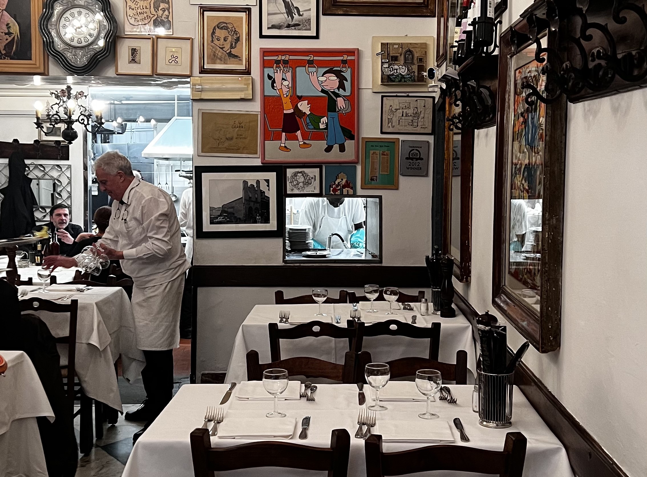 Interior of an old restaurant with art on the walls and white tablecloths