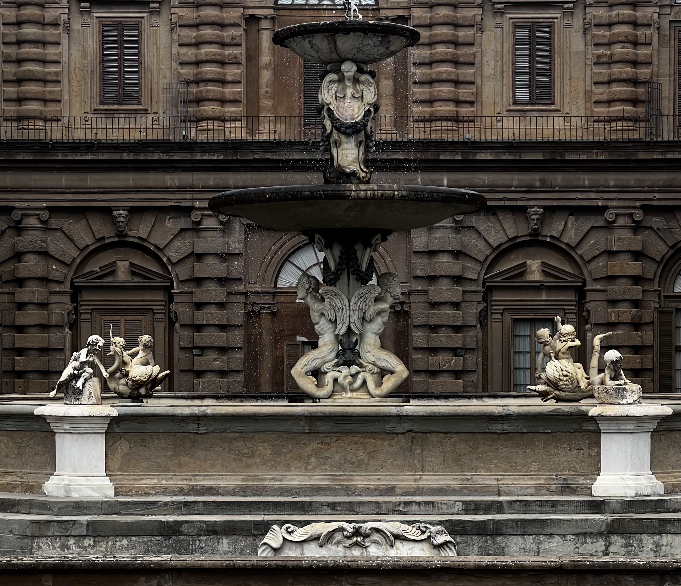 The image captures an ornate fountain with sculptures, set against the backdrop of a classical building facade.