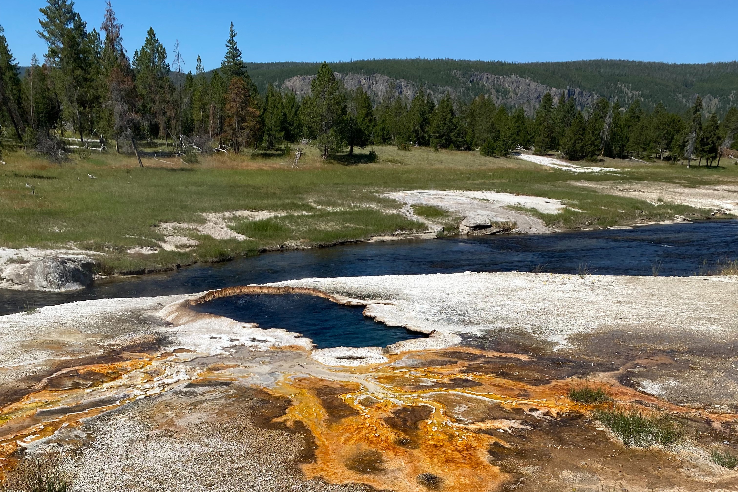 Artists Paint Pots' hiking trail with a view of a deep-blue river and natural greenery on a sunny day.