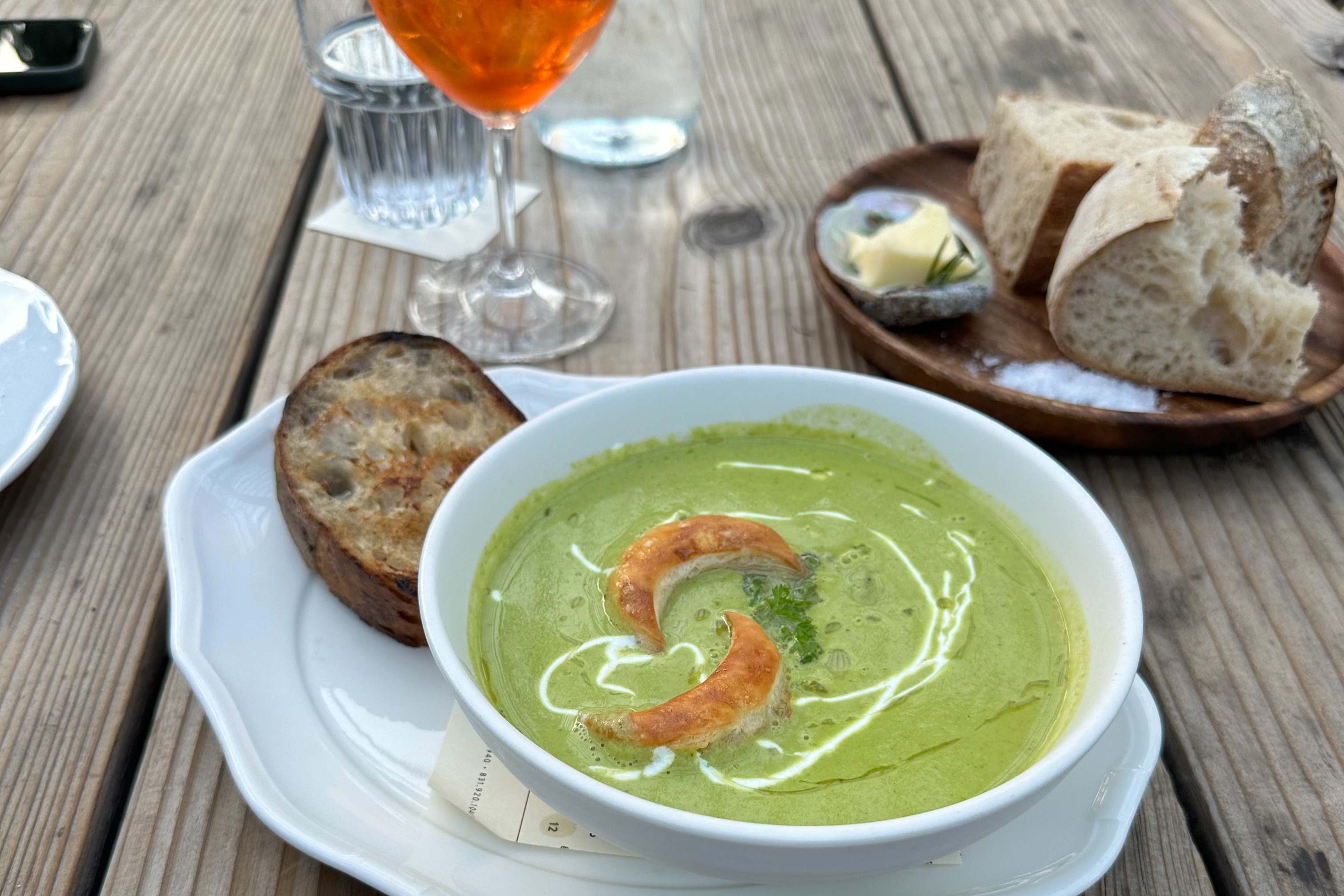 A green soup in a white bowl sitting on a table