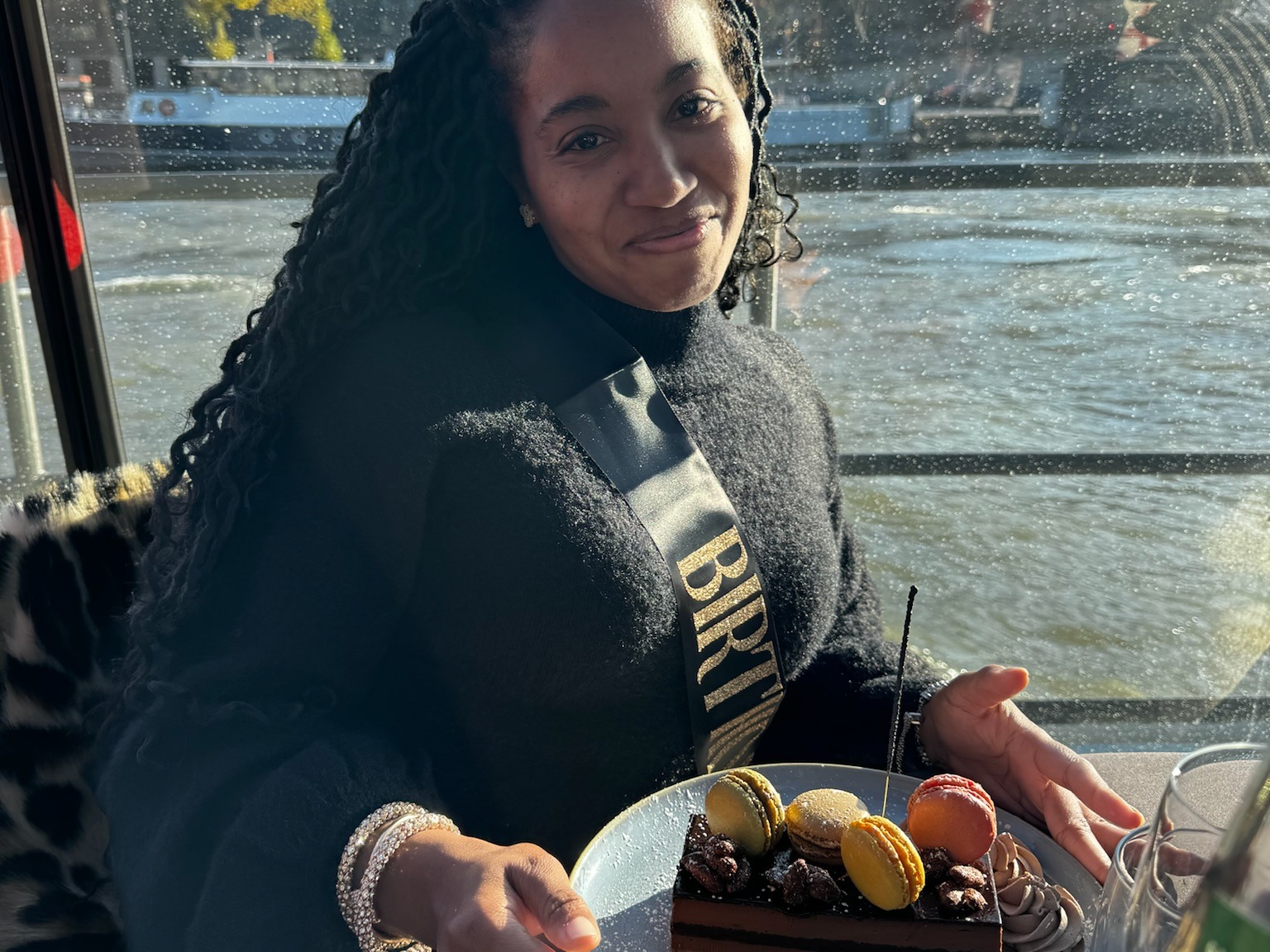 A woman with a plate of dessert with a river view.