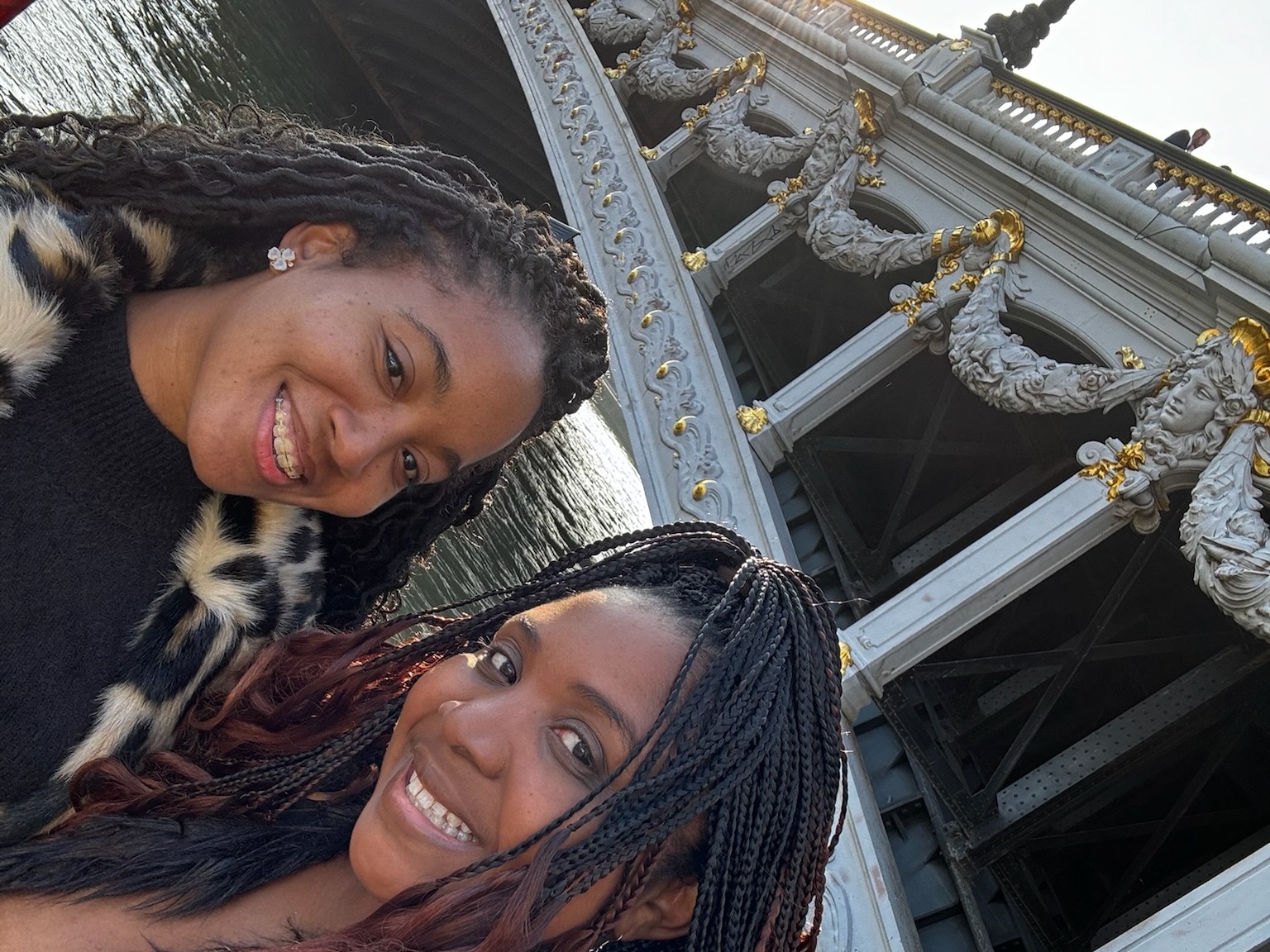 Two women posing for a selfie in front of a bridge.