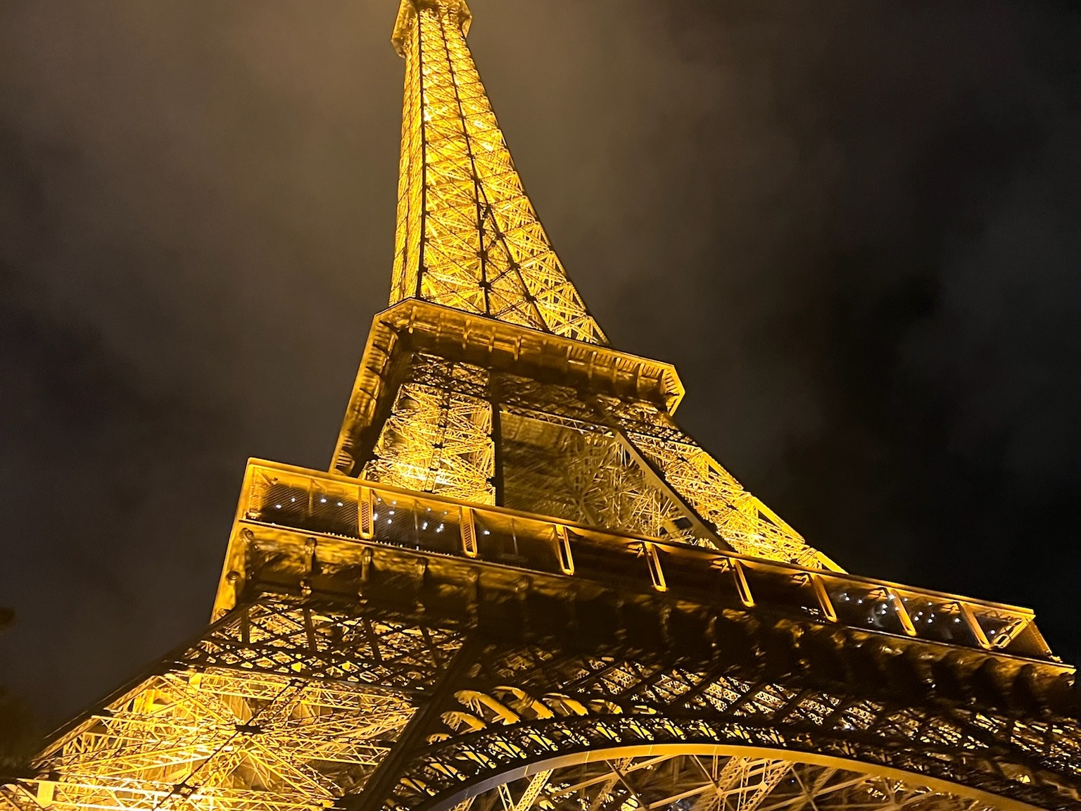 Low-angled view of the Eiffel Tower, illuminated at night.
