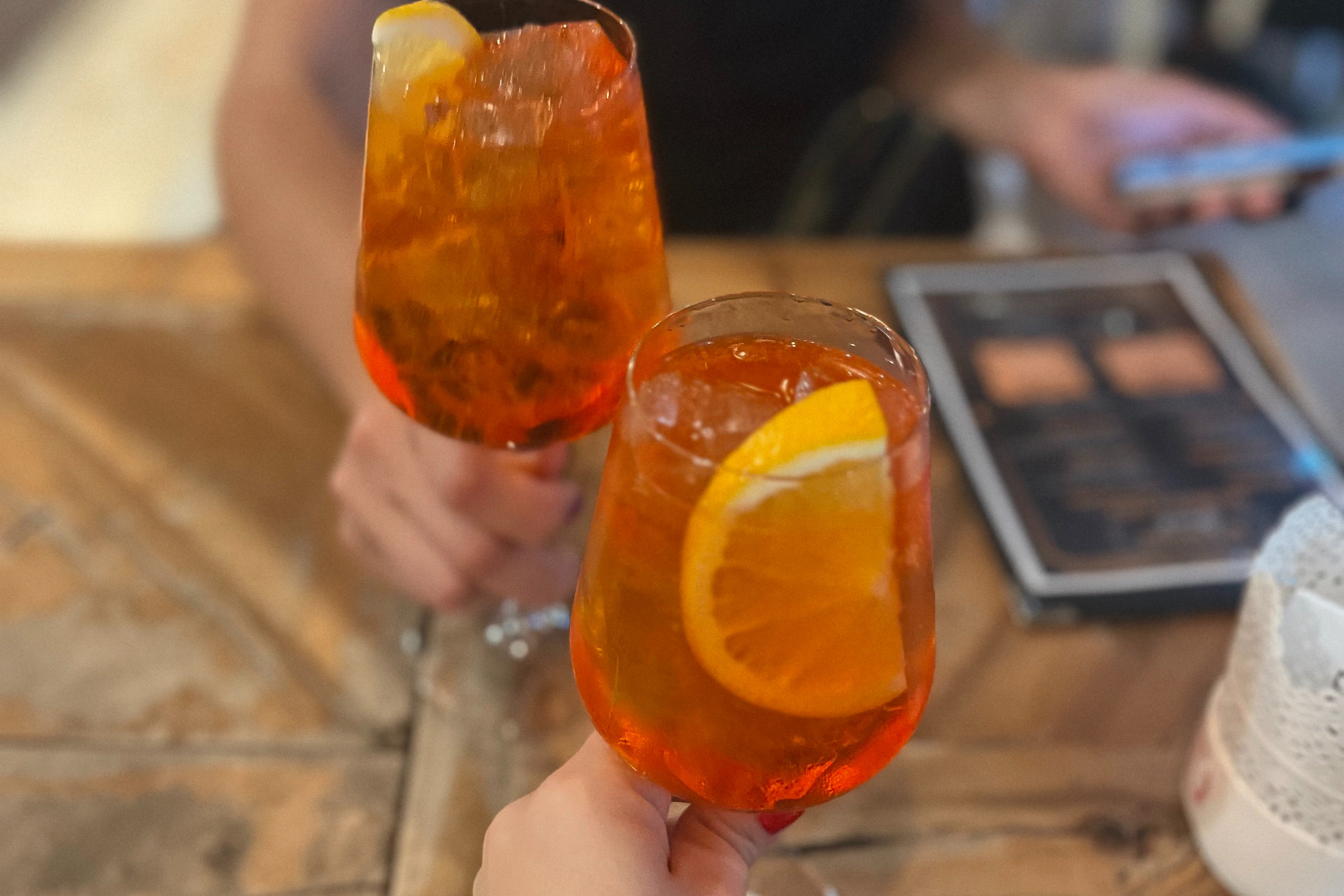 Hands cheering two wine glasses of an orange drink