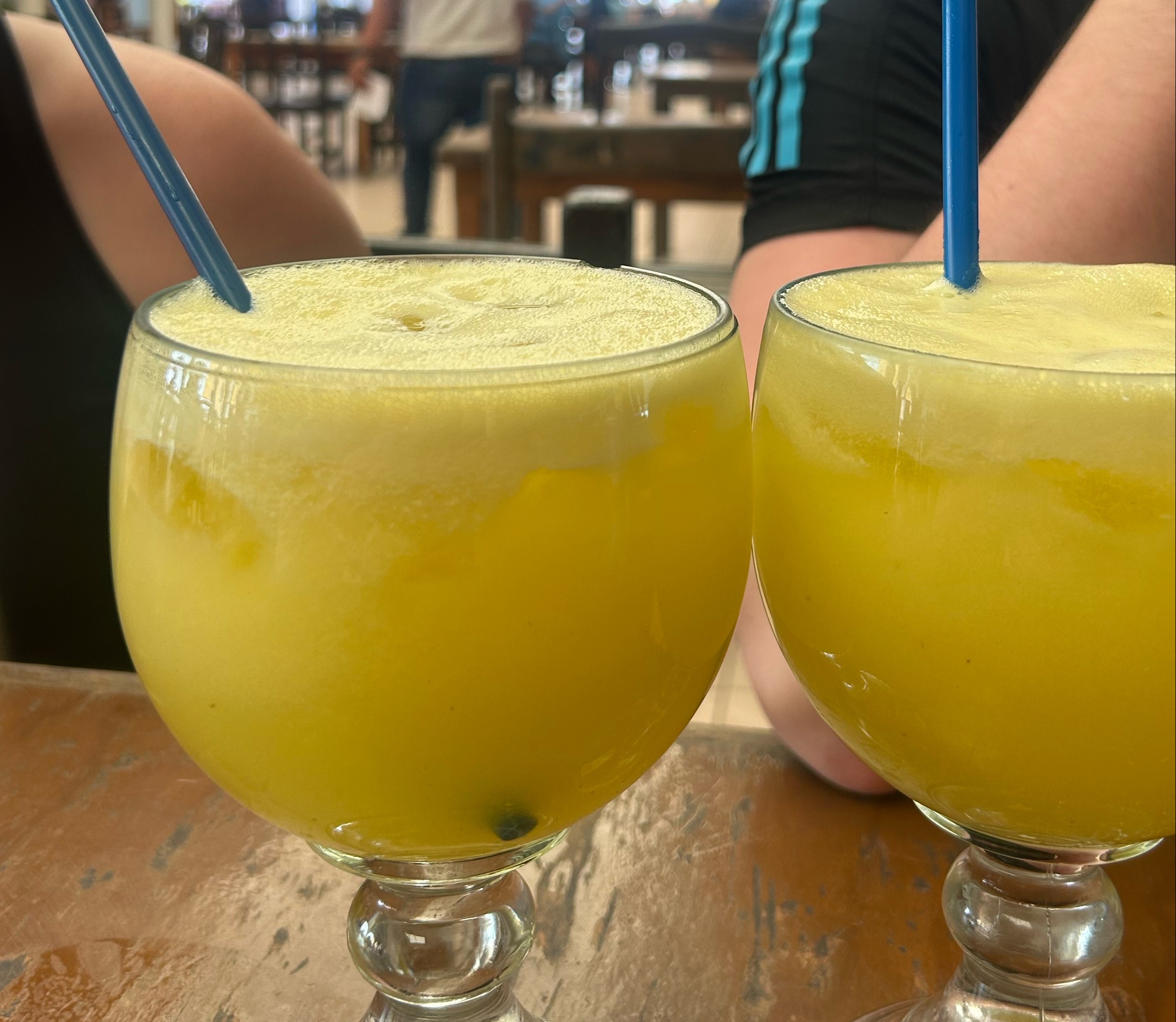 Two glasses of yellow colored juices on table.