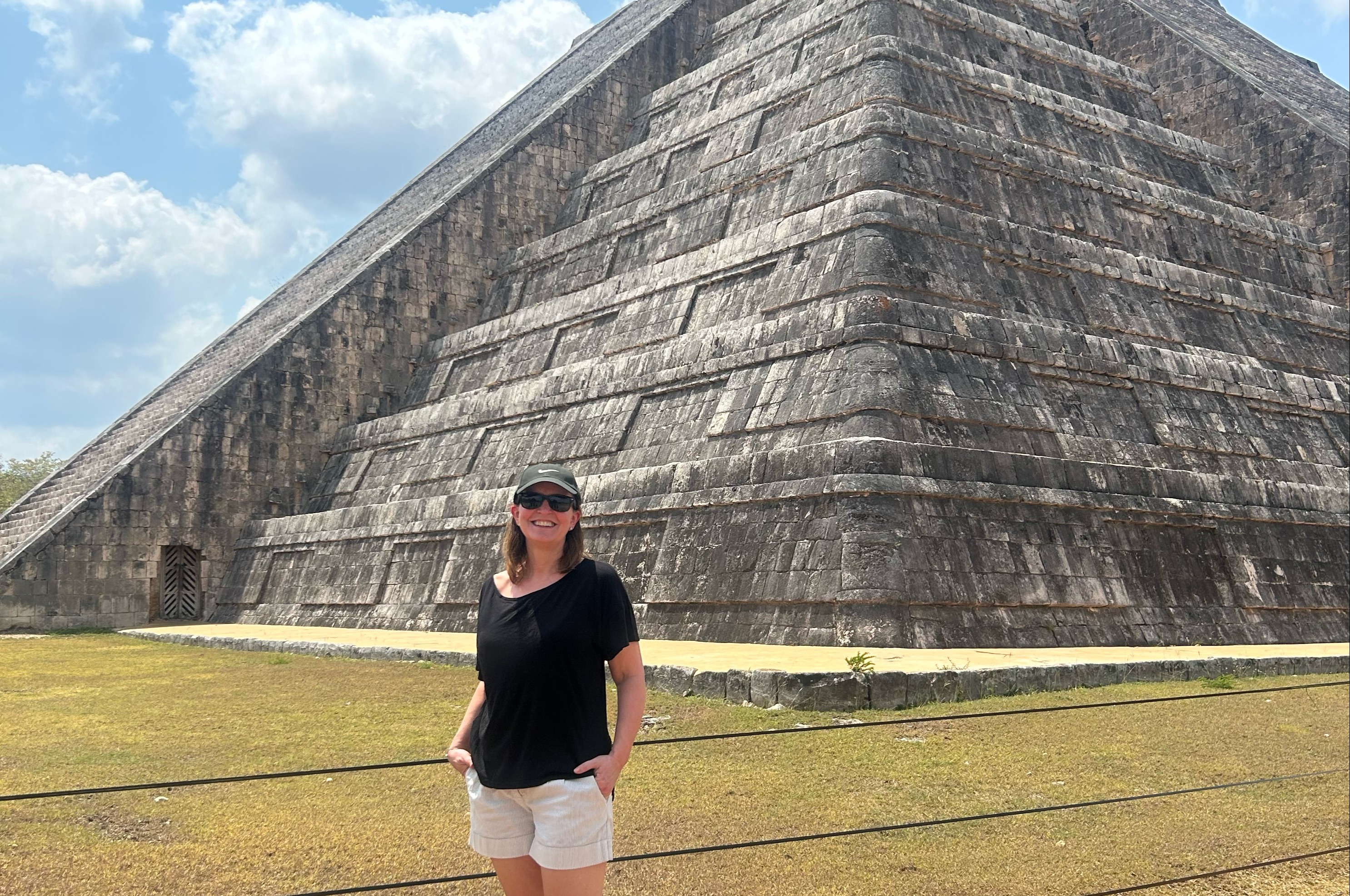 A woman standing in front of a grey triangular structure.