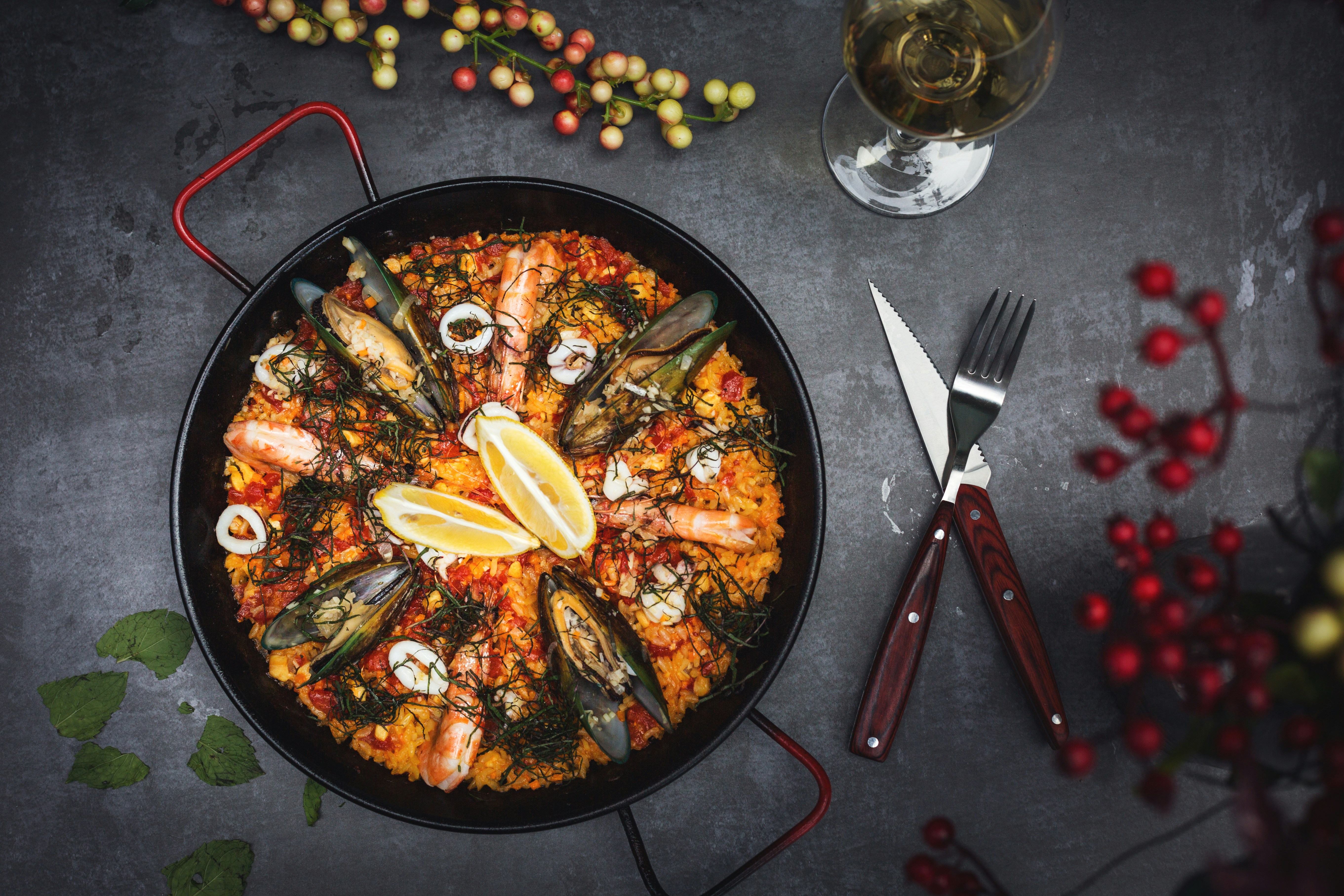 An aperol spritz, patatas bravas and olives on a table.