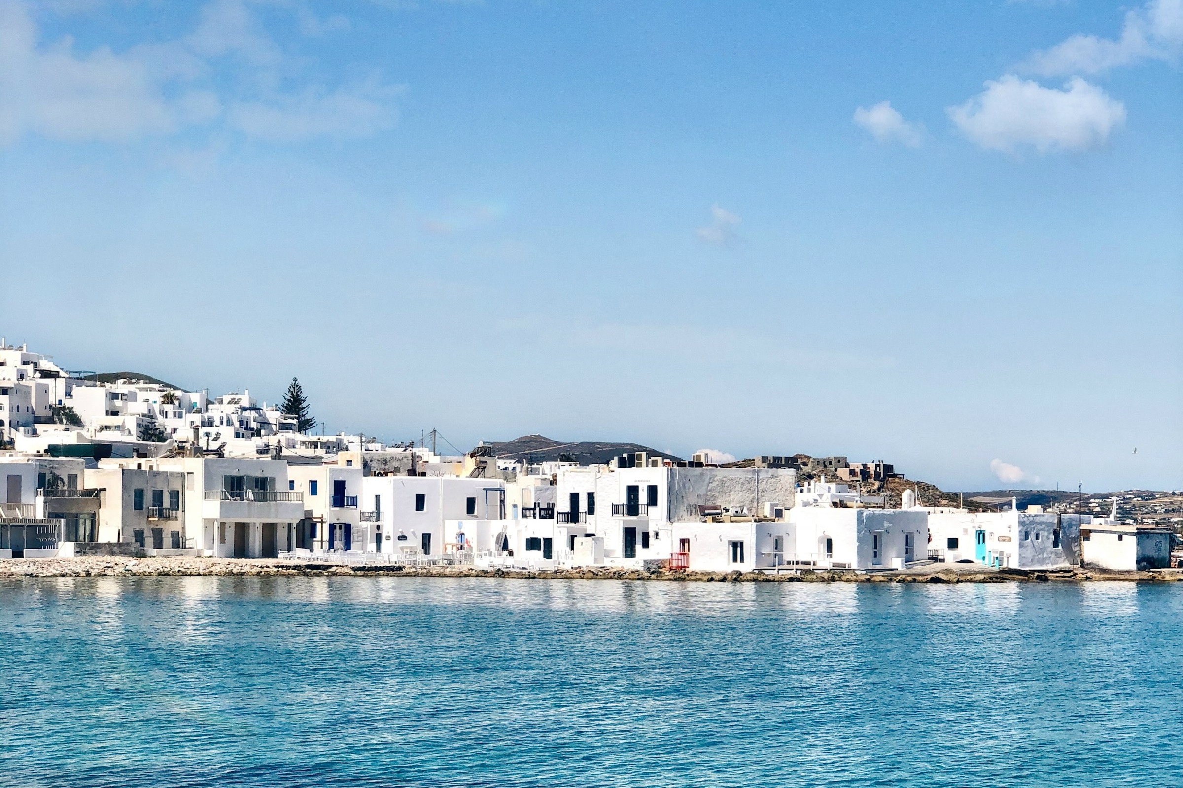 A village of white buildings next to a body of bright blue water during the daytime