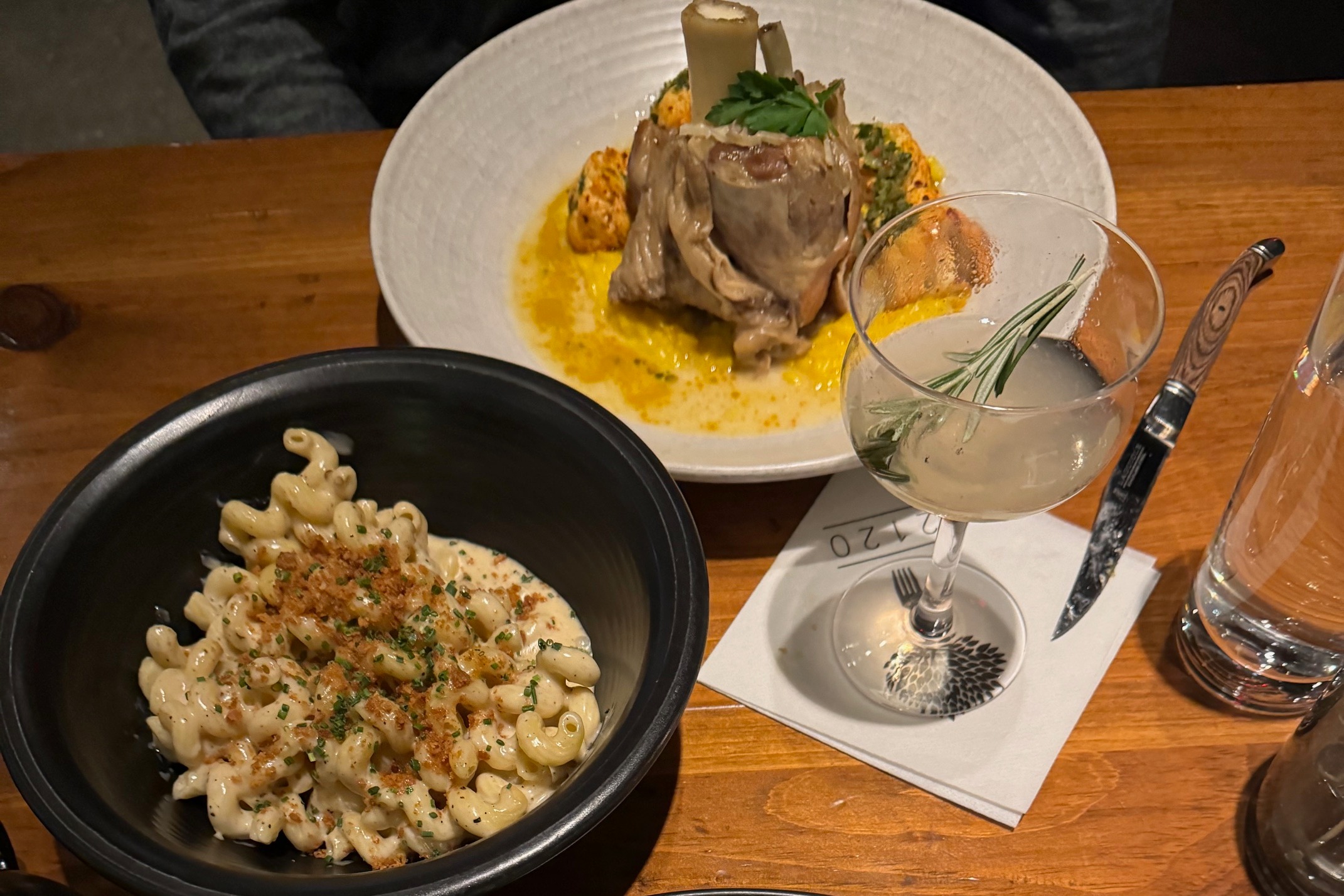 An aerial view of two dishes and a cocktail at 2120 restaurant.